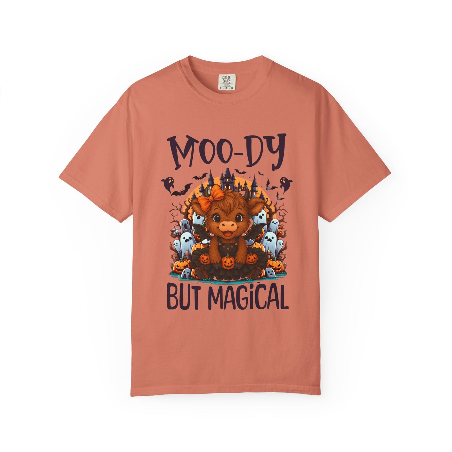 Coral t-shirt with a graphic of a cow and text 'Moo-dy But Magical' on a white background