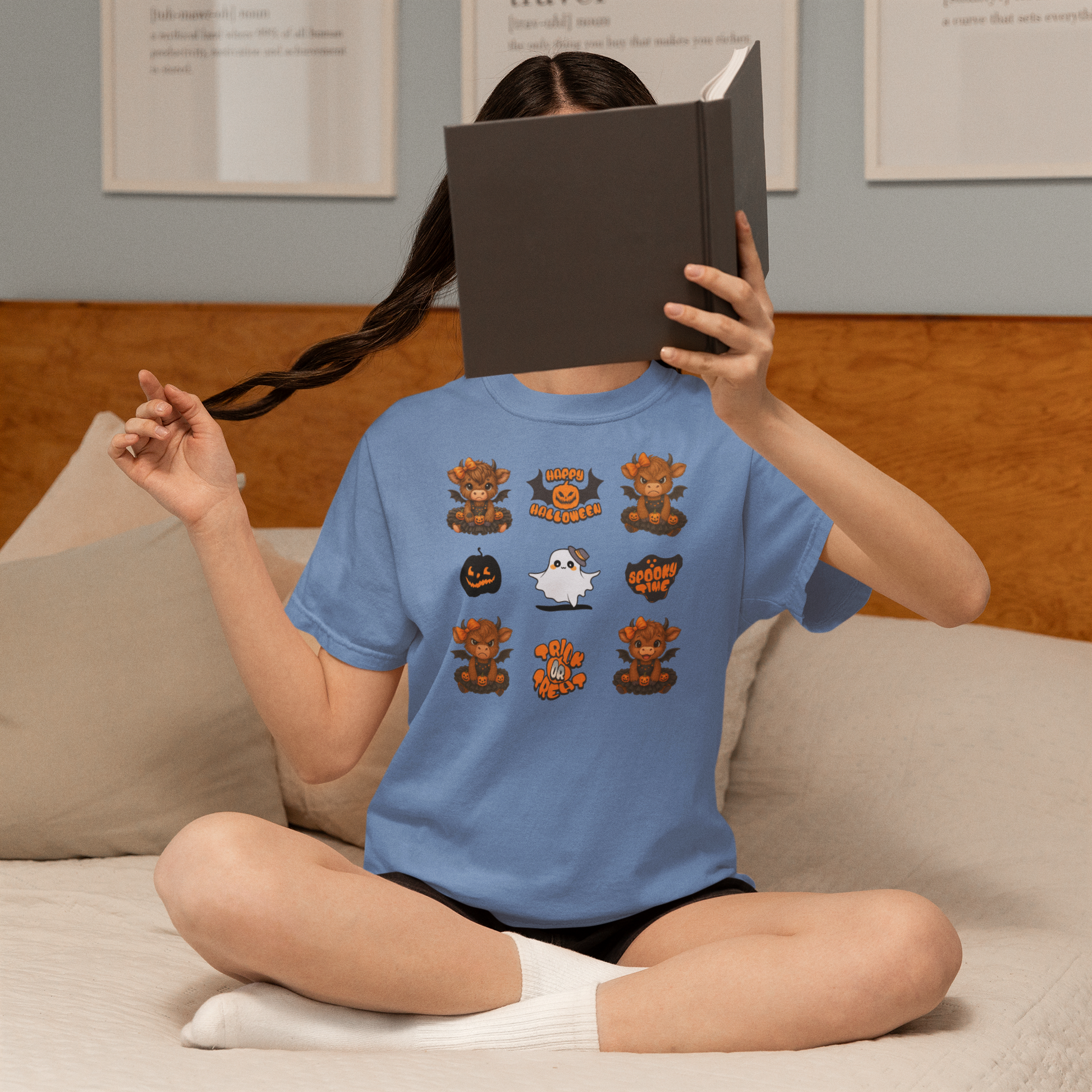 Person wearing a blue t-shirt with Halloween-themed designs sitting on a couch.