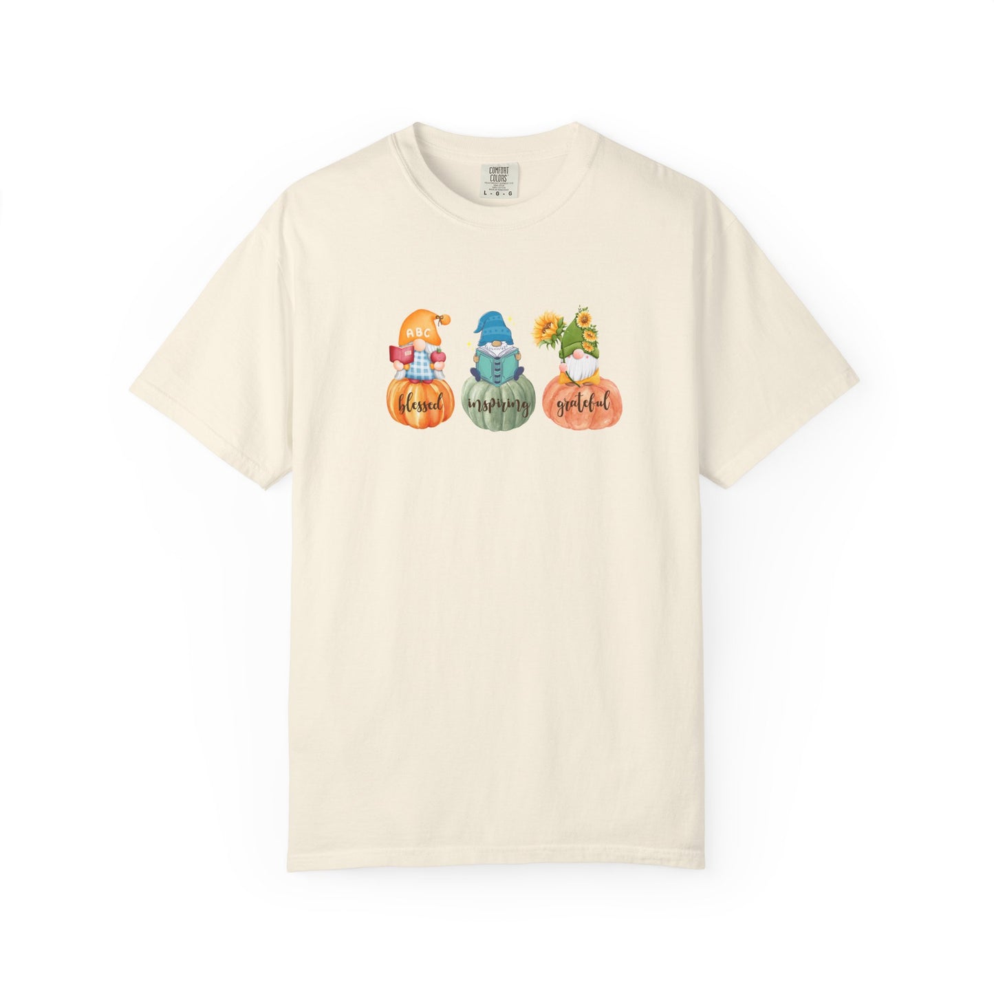 Beige t-shirt with colorful graphic of gnomes and pumpkins on a white background