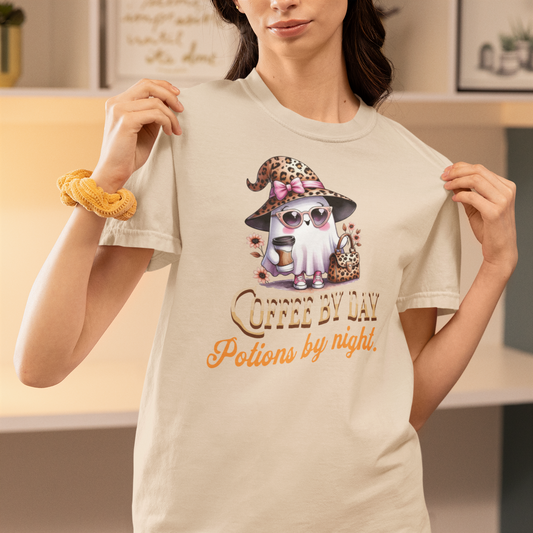 Person wearing a t-shirt with a graphic of a cat in a witch hat and sunglasses, holding the shirt.