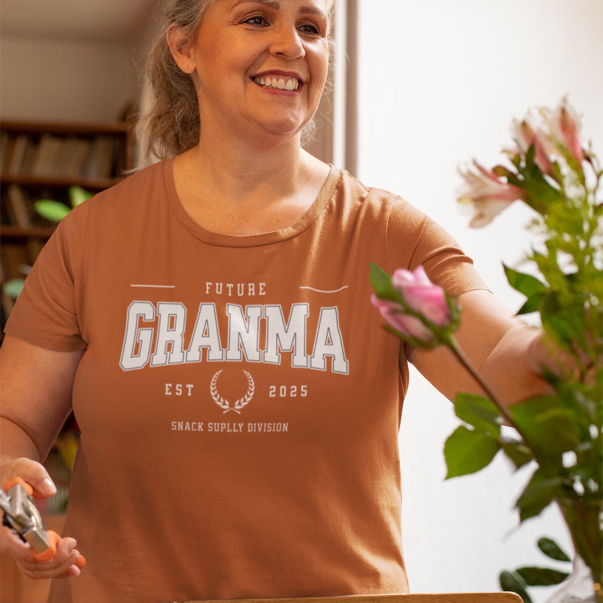 Woman wearing a 'Future Grandma' t-shirt holding flowers and gardening shears.