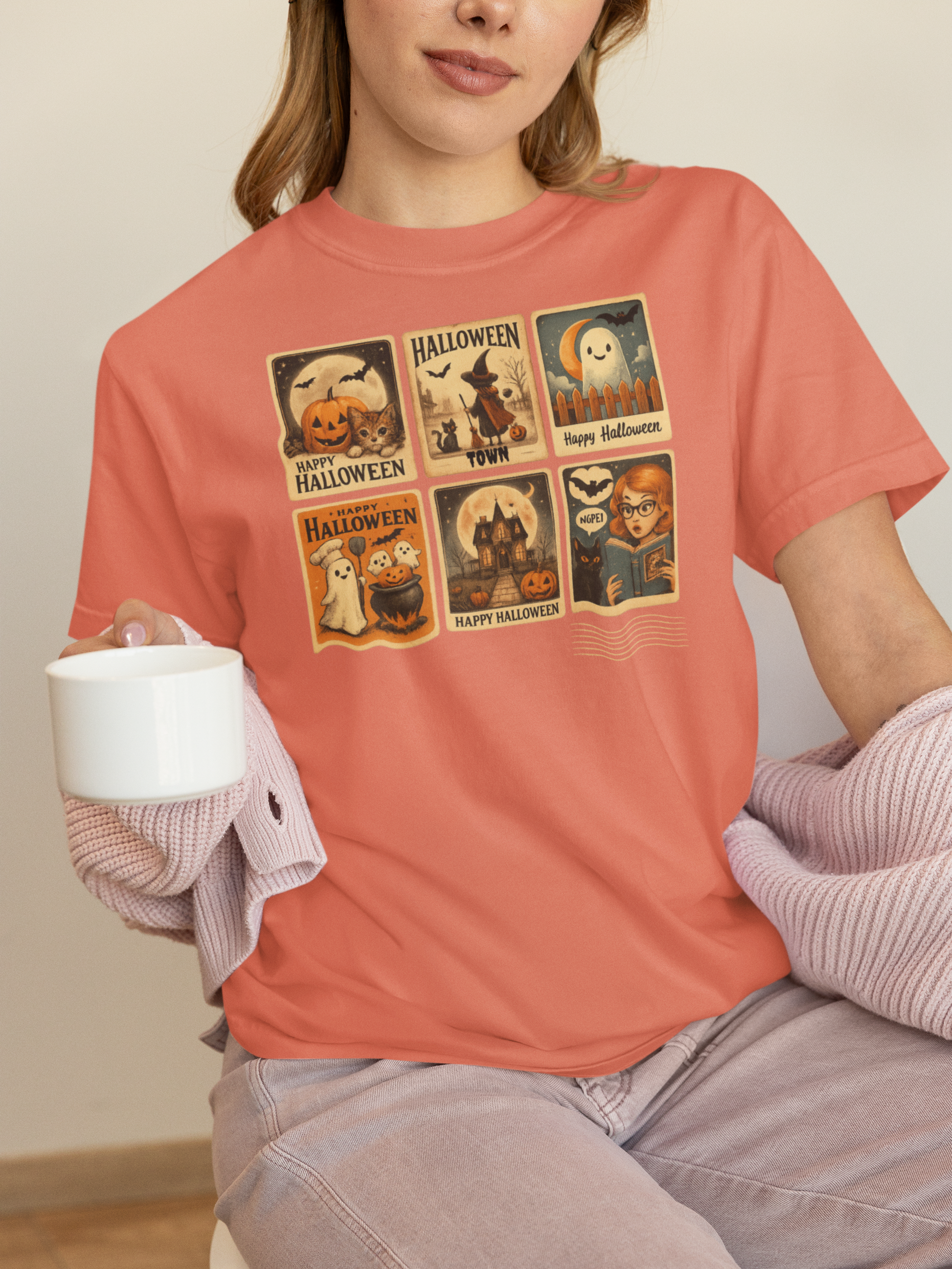 Person wearing a coral t-shirt with Halloween-themed graphic, holding a white mug.