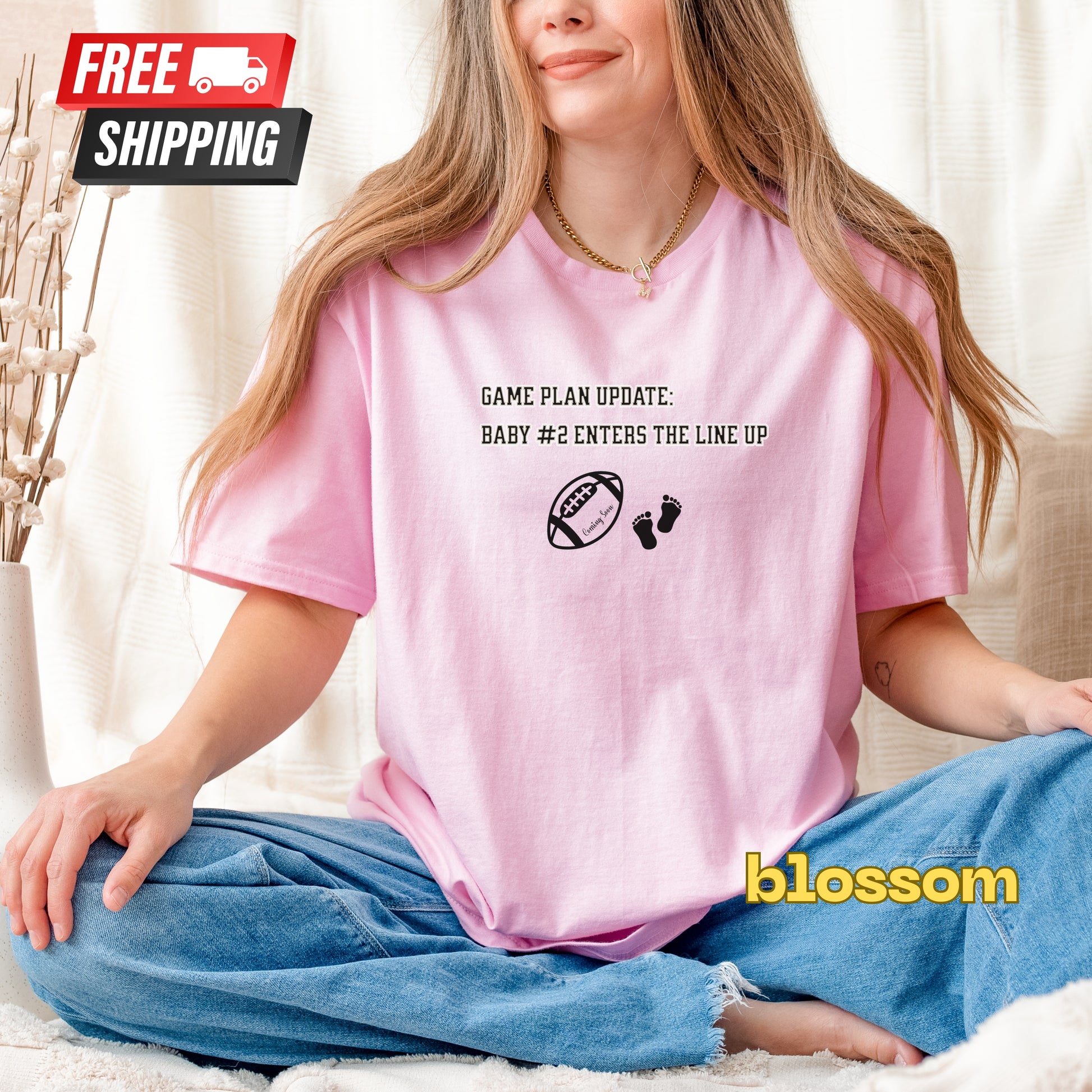 Person wearing a pink t-shirt with text and graphics, sitting on a couch.