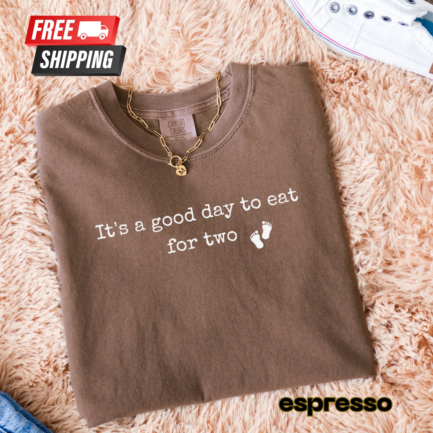 Folded brown shirt with 'It's a good day to eat for two' text on a fluffy beige surface, with 'espresso' branding.