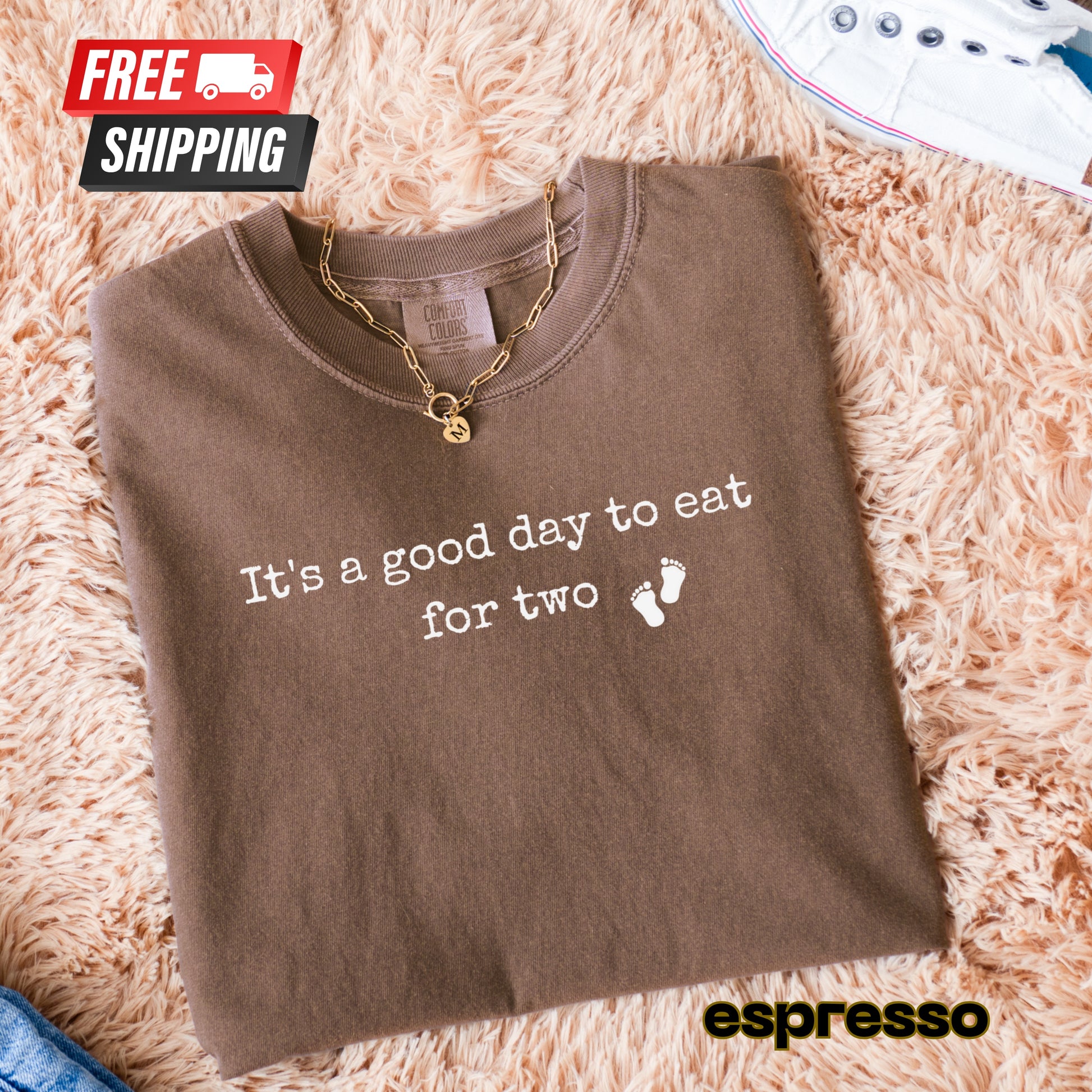 Folded brown shirt with 'It's a good day to eat for two' text on a fluffy beige surface, with 'espresso' branding.