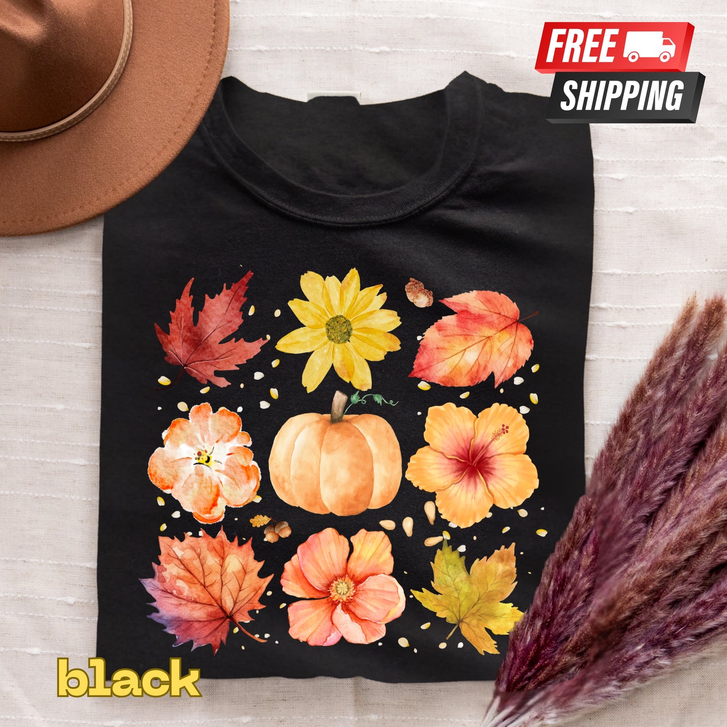 Black t-shirt with autumn-themed design featuring pumpkins and leaves on a light wooden surface.