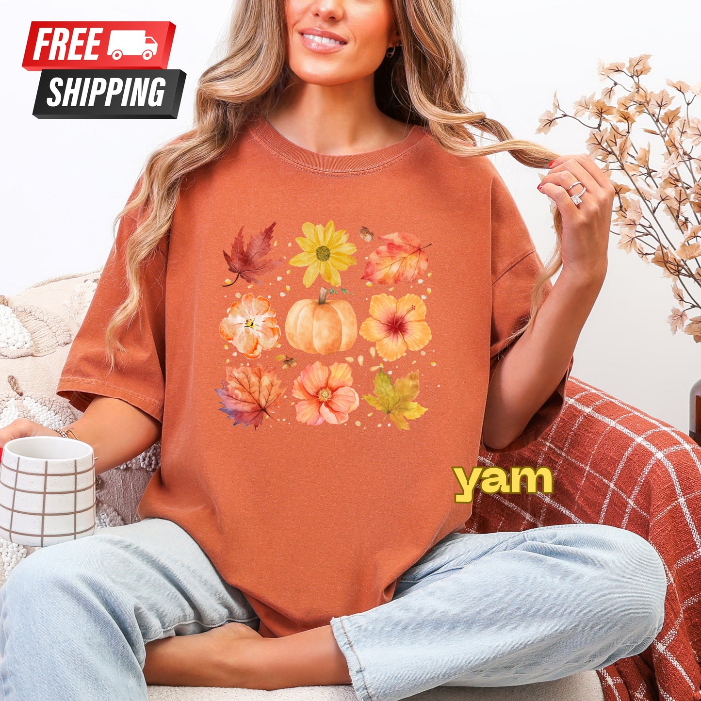 Person wearing a brown t-shirt with autumn-themed design and 'yam' text, sitting on a couch.