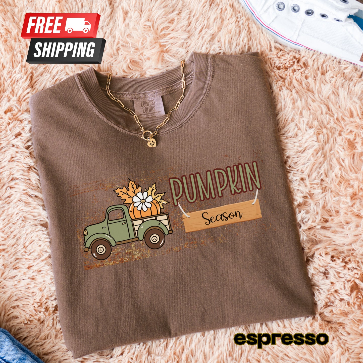 Folded brown sweatshirt with 'Pumpkin Season' design on a fluffy beige surface, featuring free shipping text.