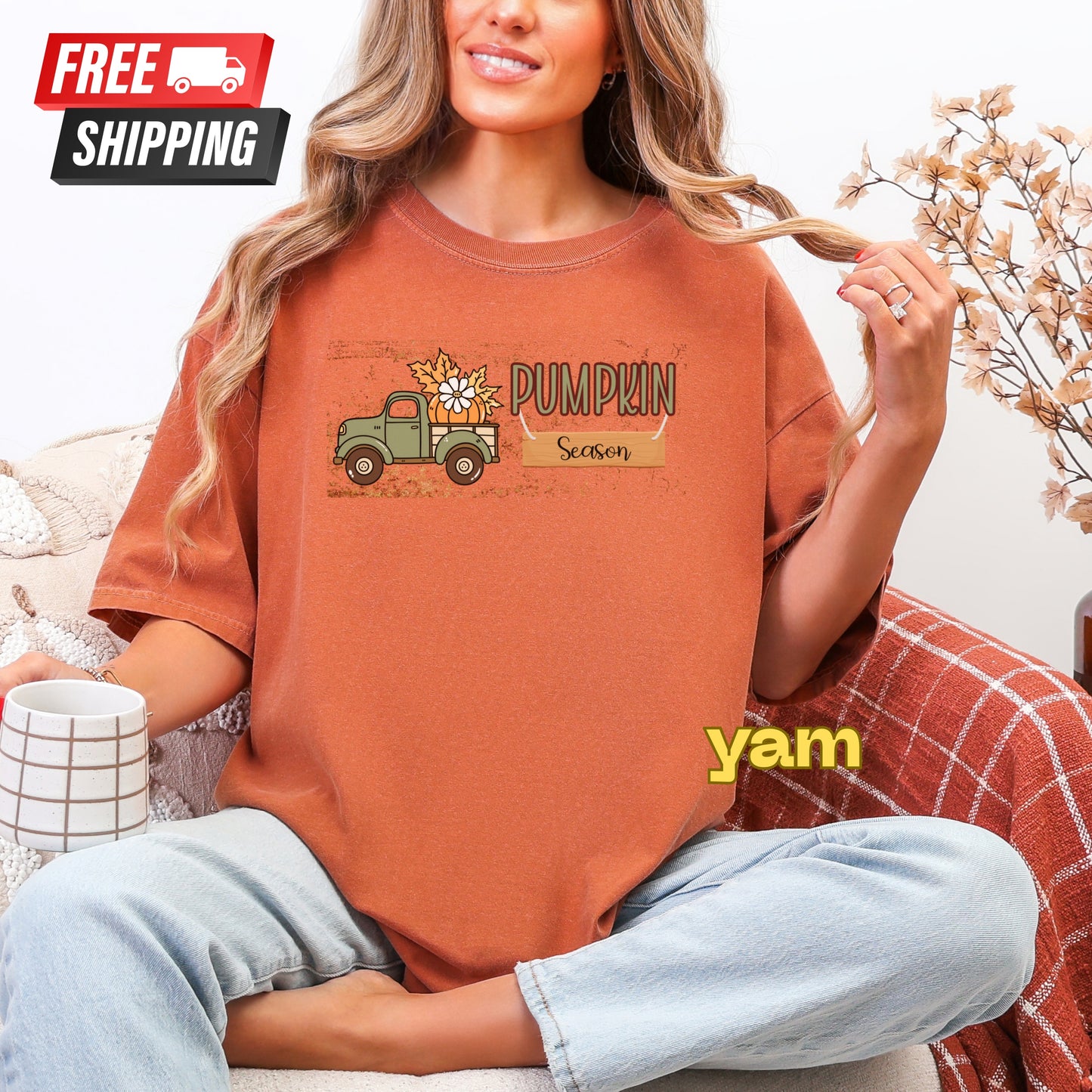 Person wearing a brown t-shirt with a pumpkin truck graphic and 'Pumpkin Season' text, sitting on a couch.