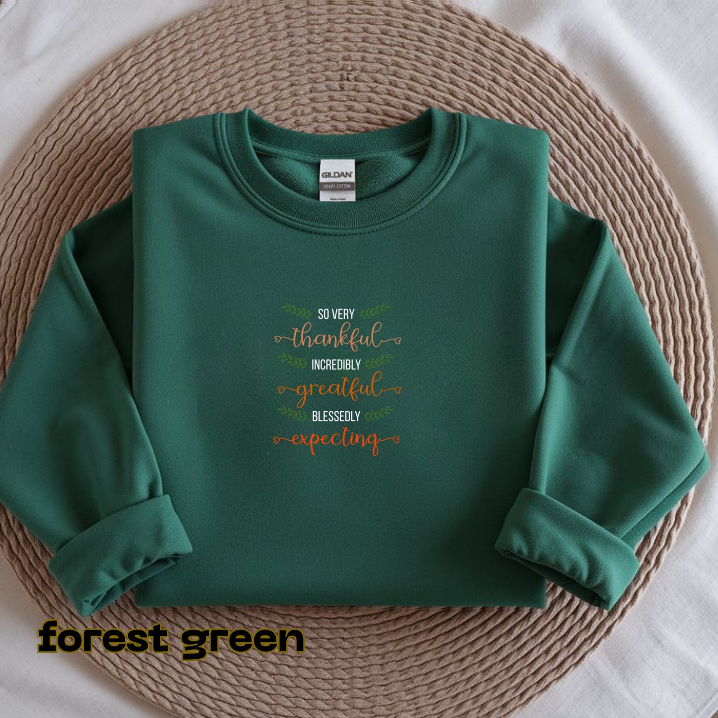 Folded green sweatshirt with text on a woven mat