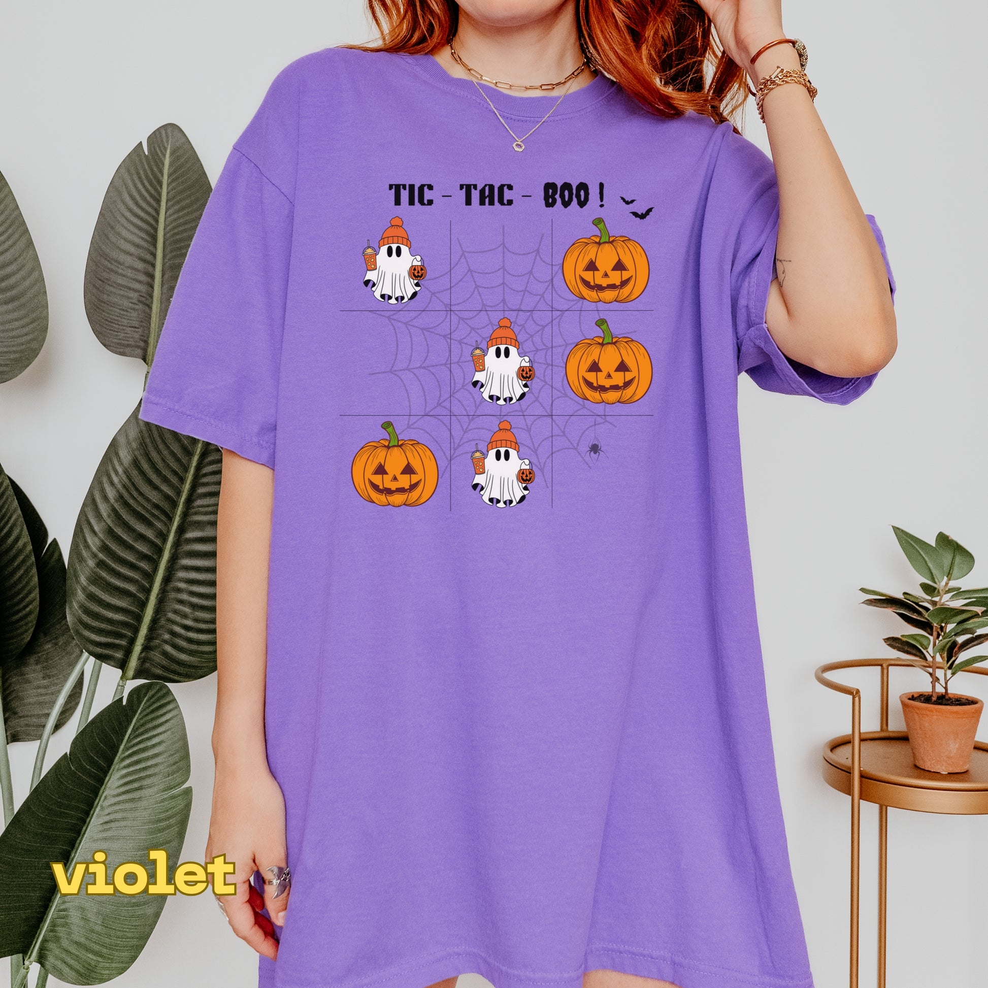 Person wearing a purple t-shirt with Halloween-themed graphics and text.