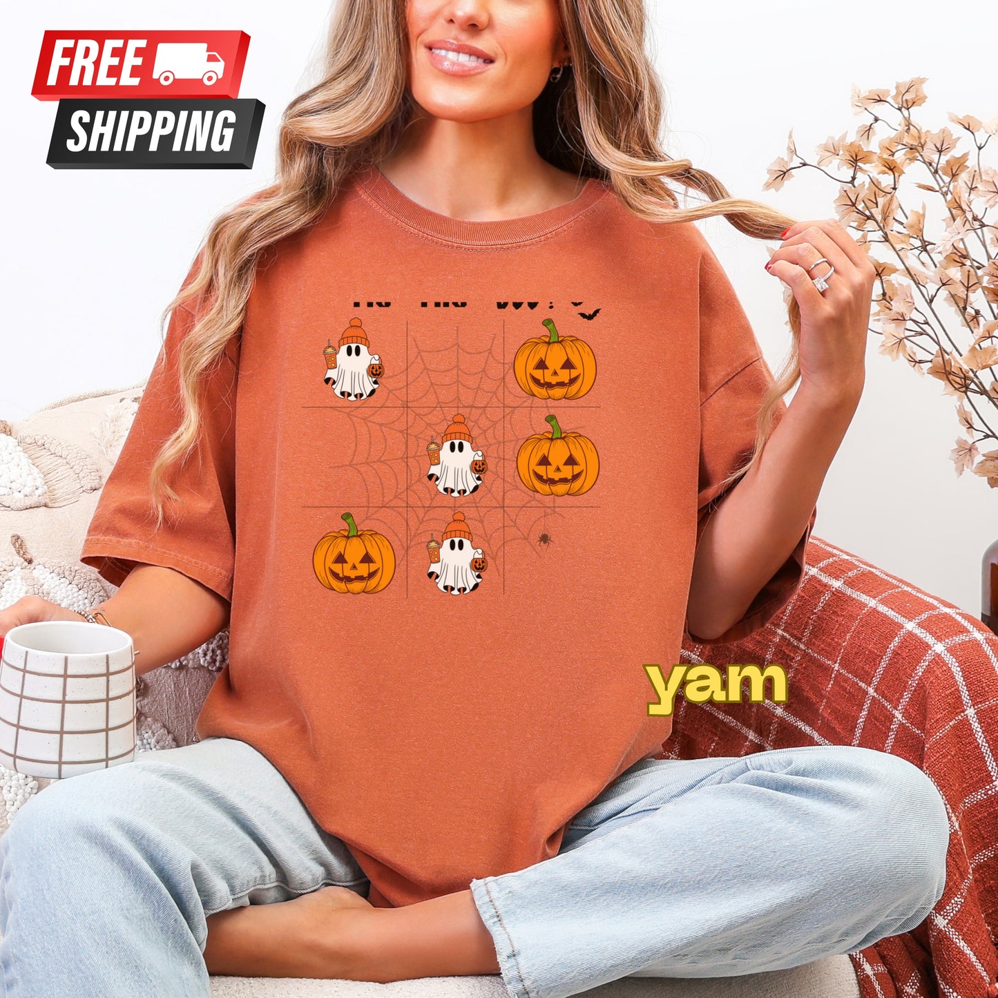 Person wearing a Halloween-themed t-shirt with pumpkins and ghosts, sitting on a couch.