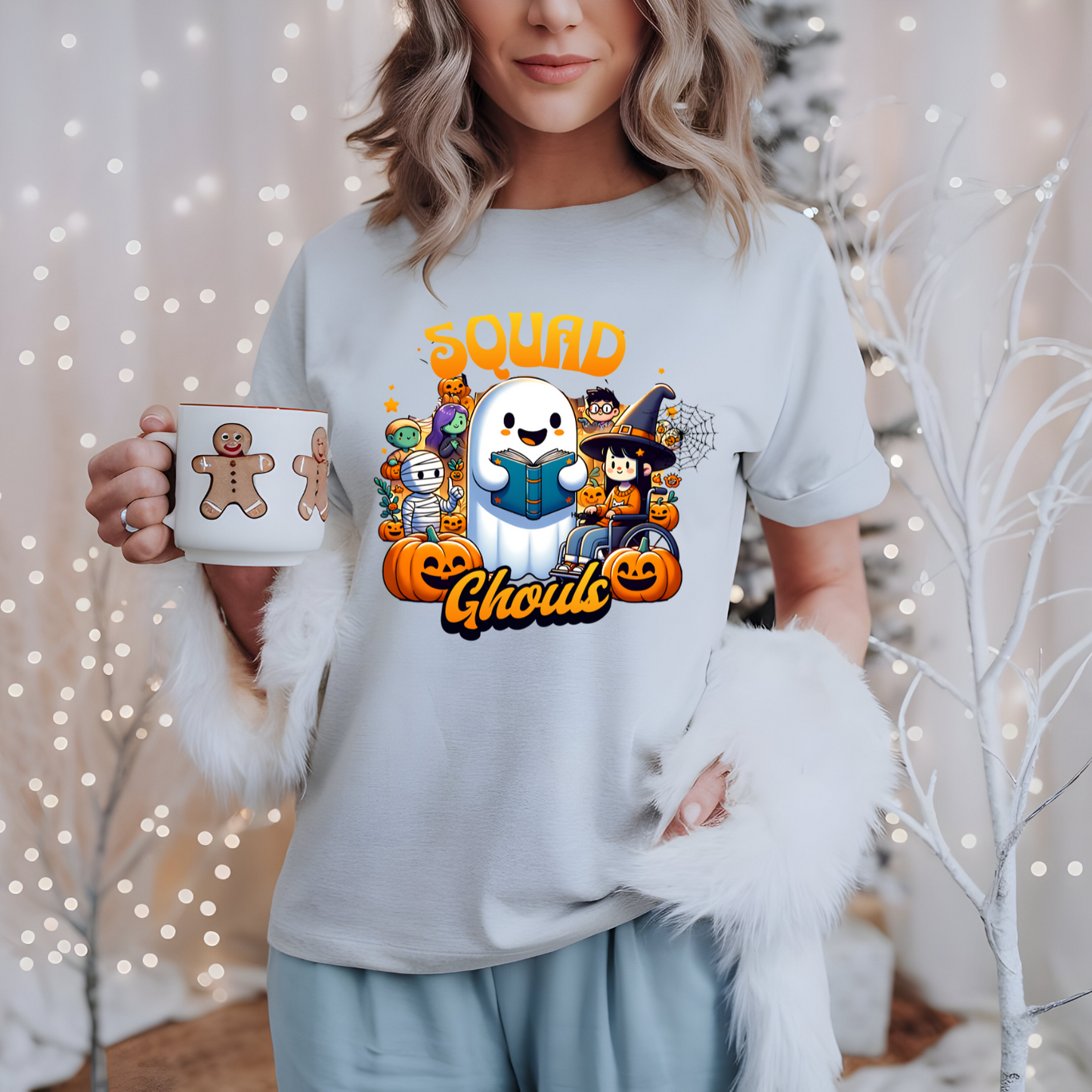 Person wearing a light blue t-shirt with Halloween-themed graphics and holding a mug.