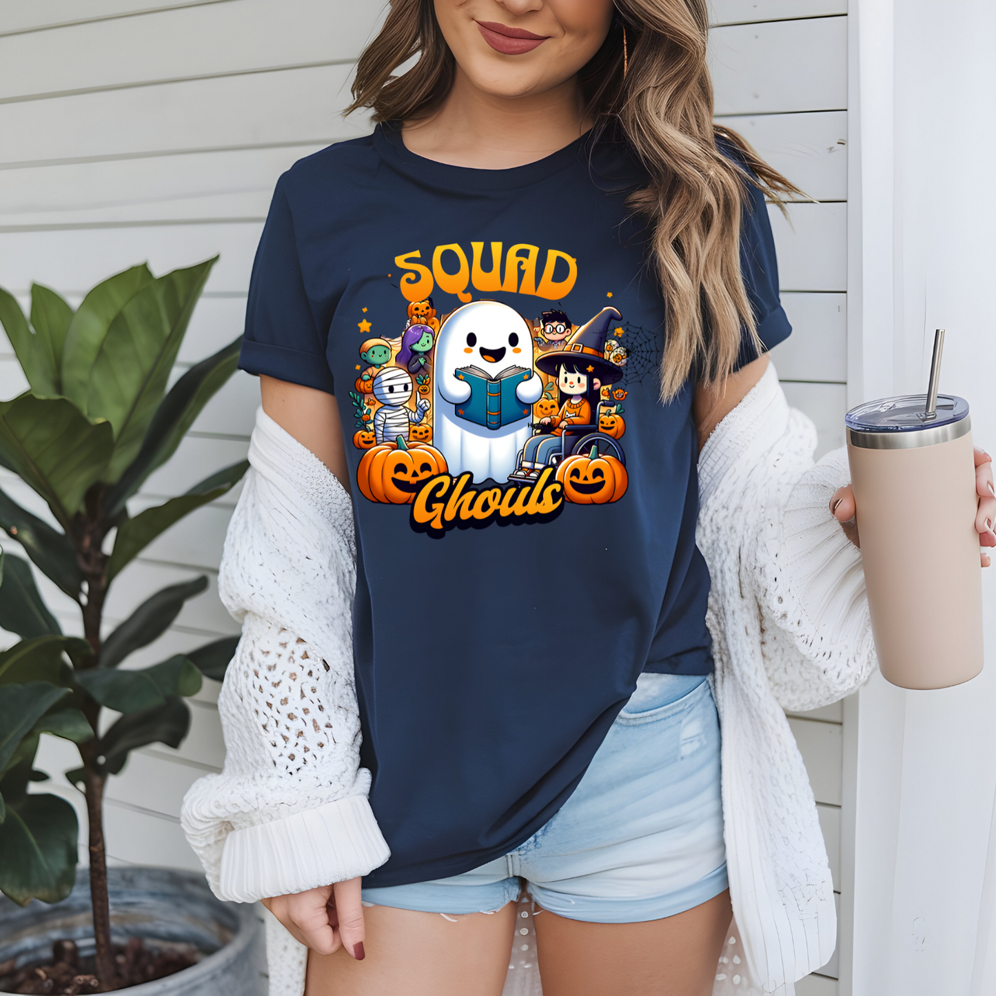Person wearing a navy blue t-shirt with Halloween-themed graphics and text, holding a cup.
