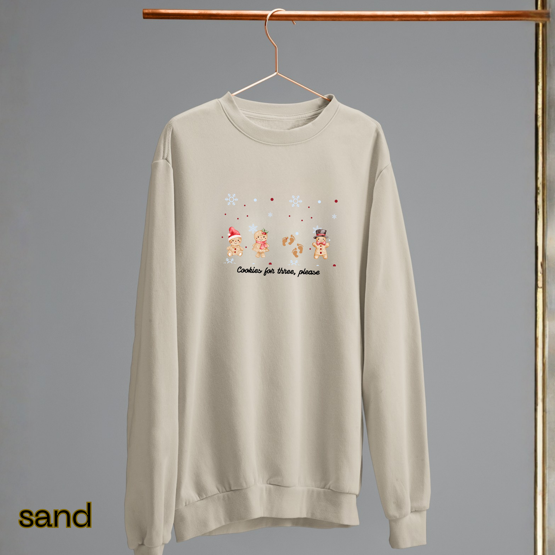 Beige sweatshirt with Christmas-themed design on a hanger against a gray background