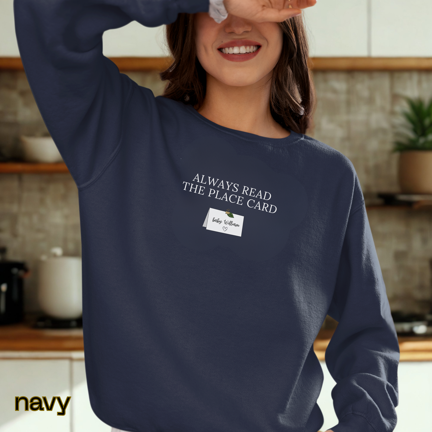 Person wearing a navy sweatshirt with text in a kitchen setting
