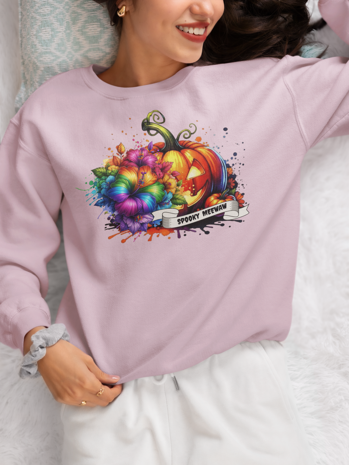 Person wearing a light purple sweatshirt with a colorful pumpkin design and text.