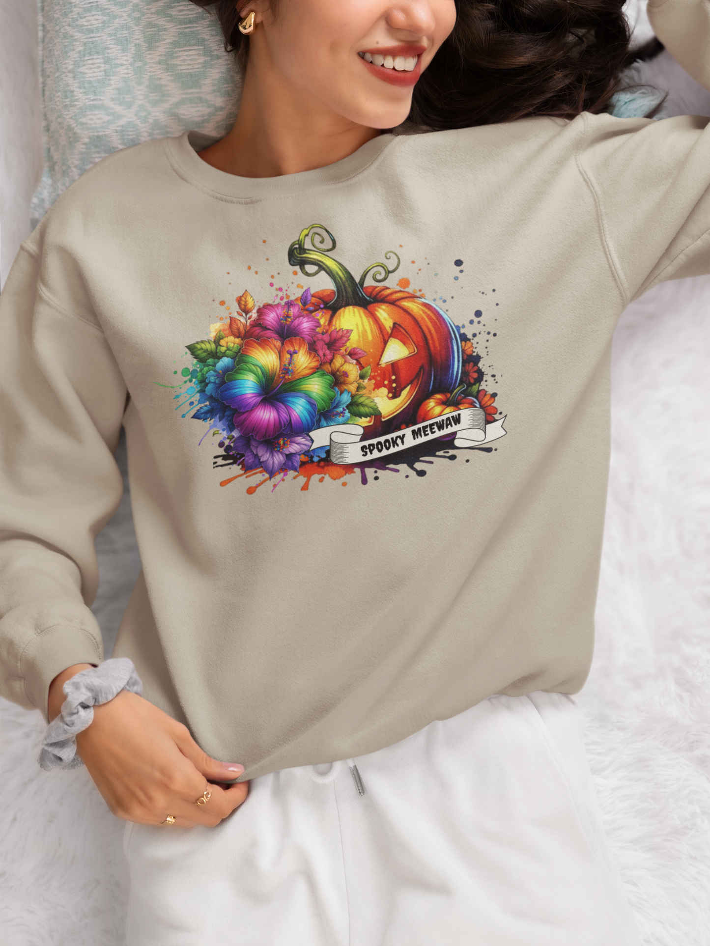 Person wearing a beige sweatshirt with a colorful pumpkin design and text.