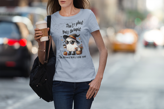 Woman wearing a t-shirt with a graphic and text, holding a coffee cup on a city street.