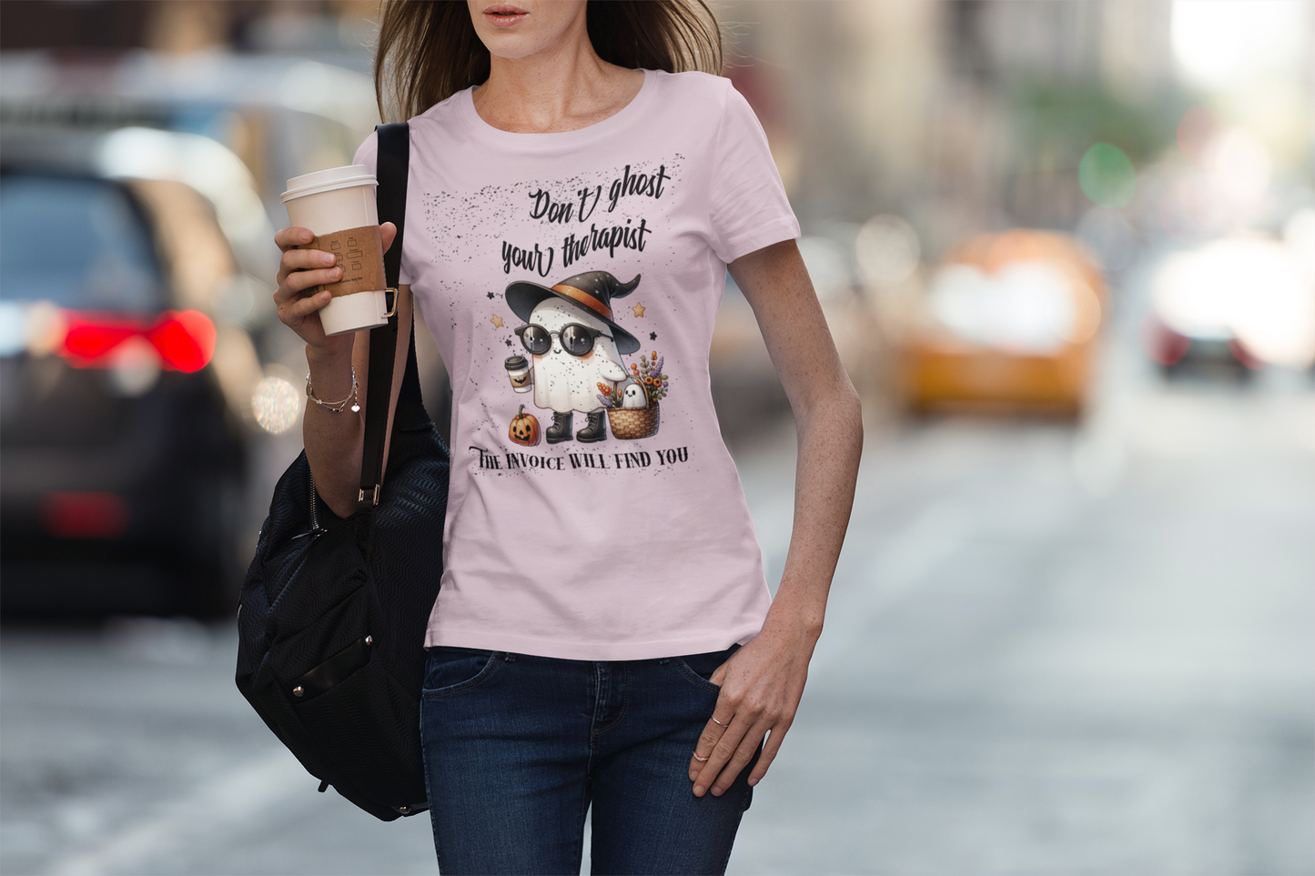 Woman wearing a pink t-shirt with a graphic and text, walking on a street.