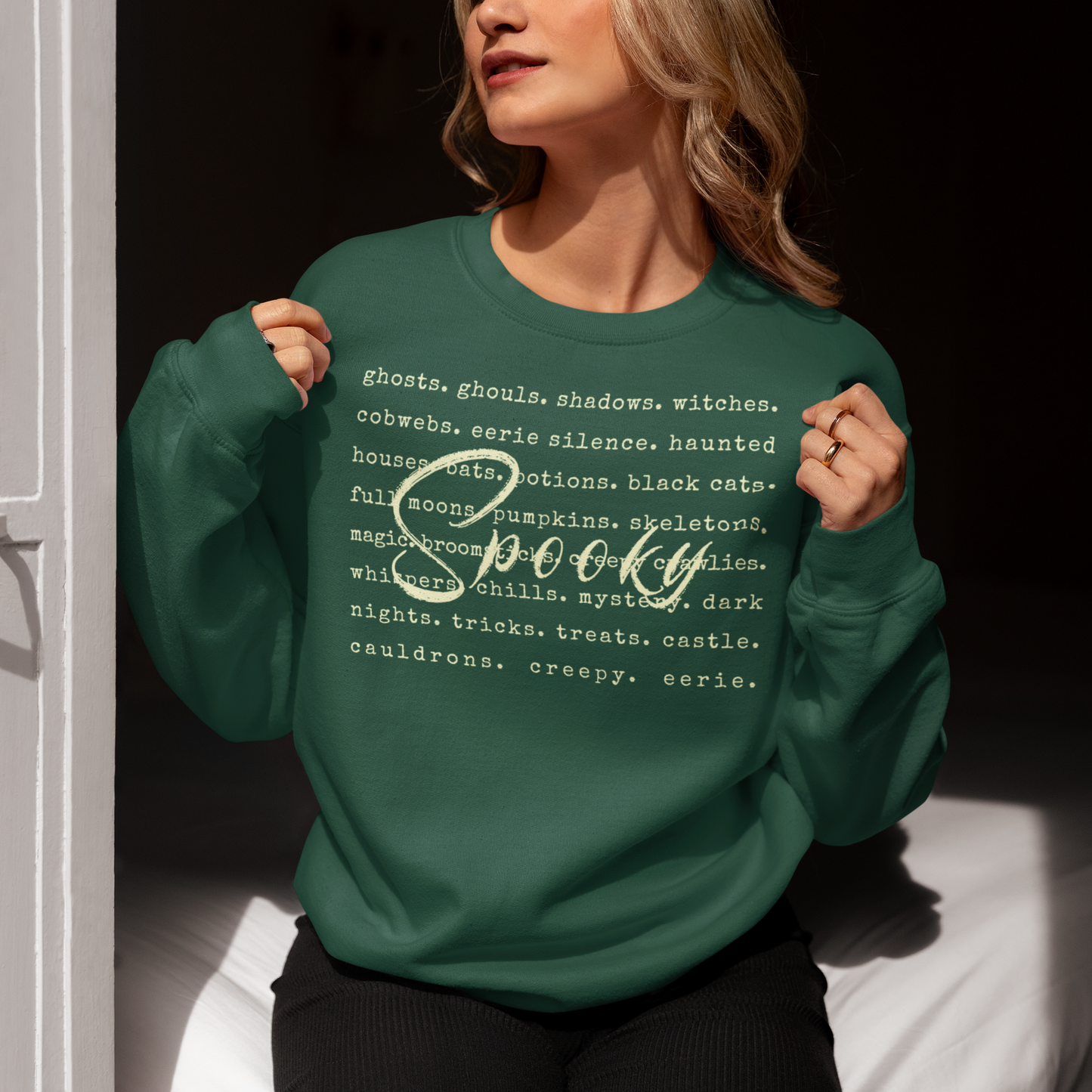 Person wearing a green sweatshirt with Halloween-themed text design.