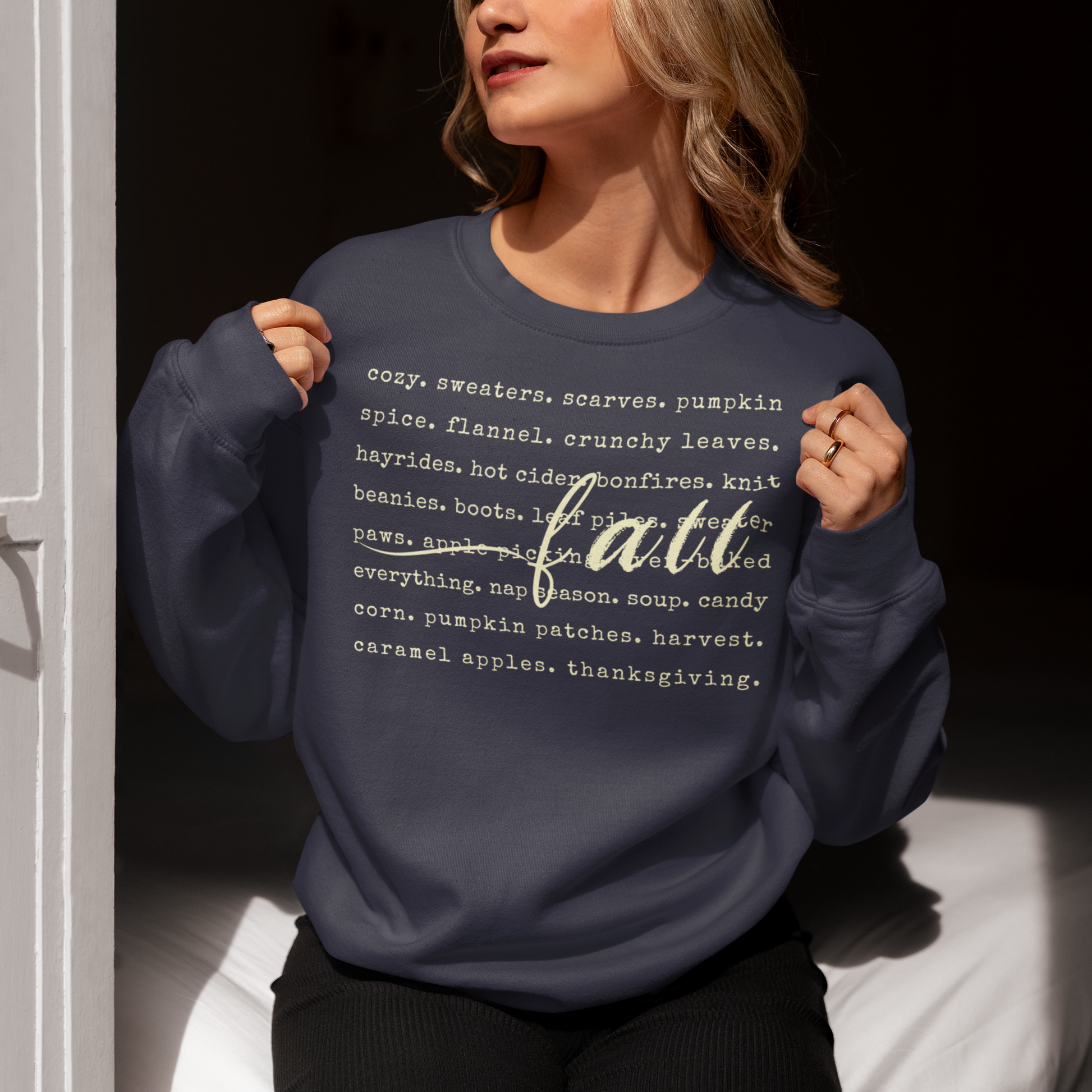 Person wearing a navy blue sweatshirt with 'fall' and related words printed on it.