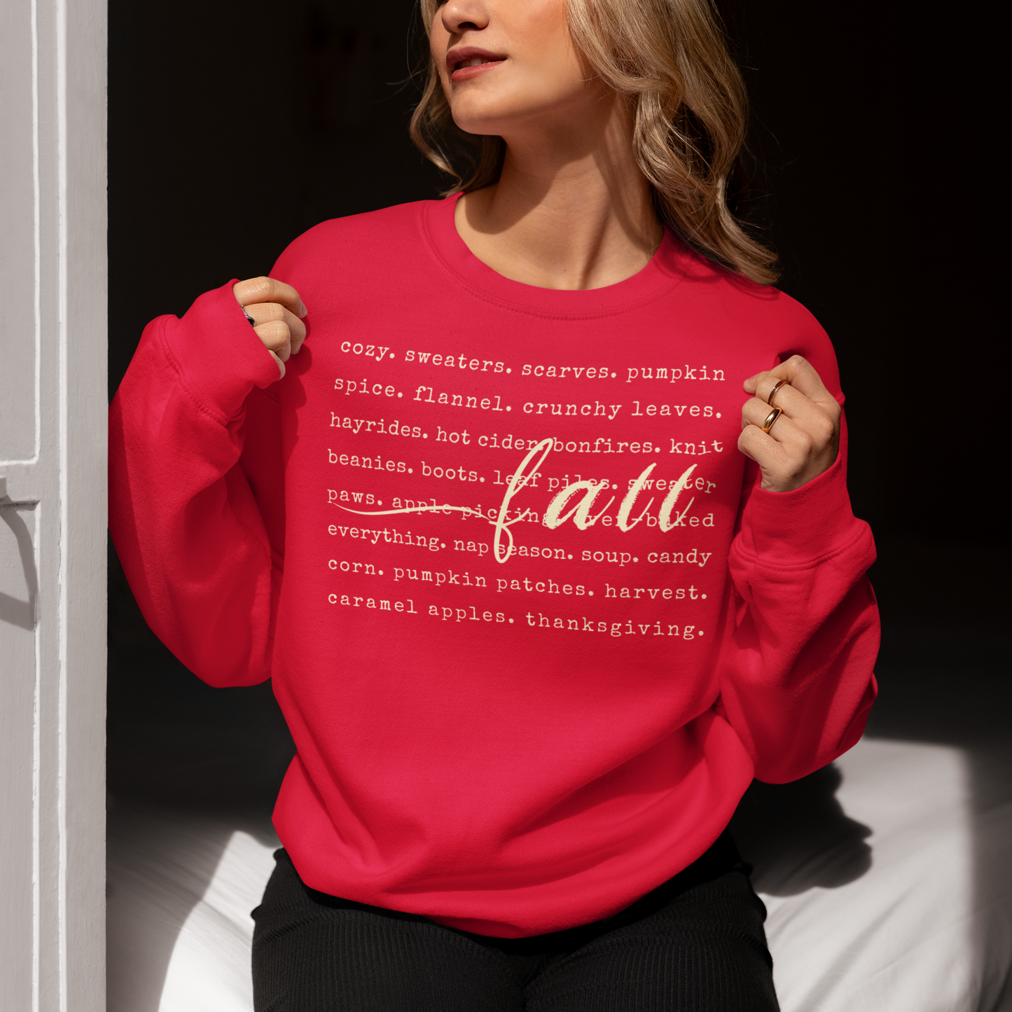 Person wearing a red sweatshirt with 'fall' and related words printed on it.