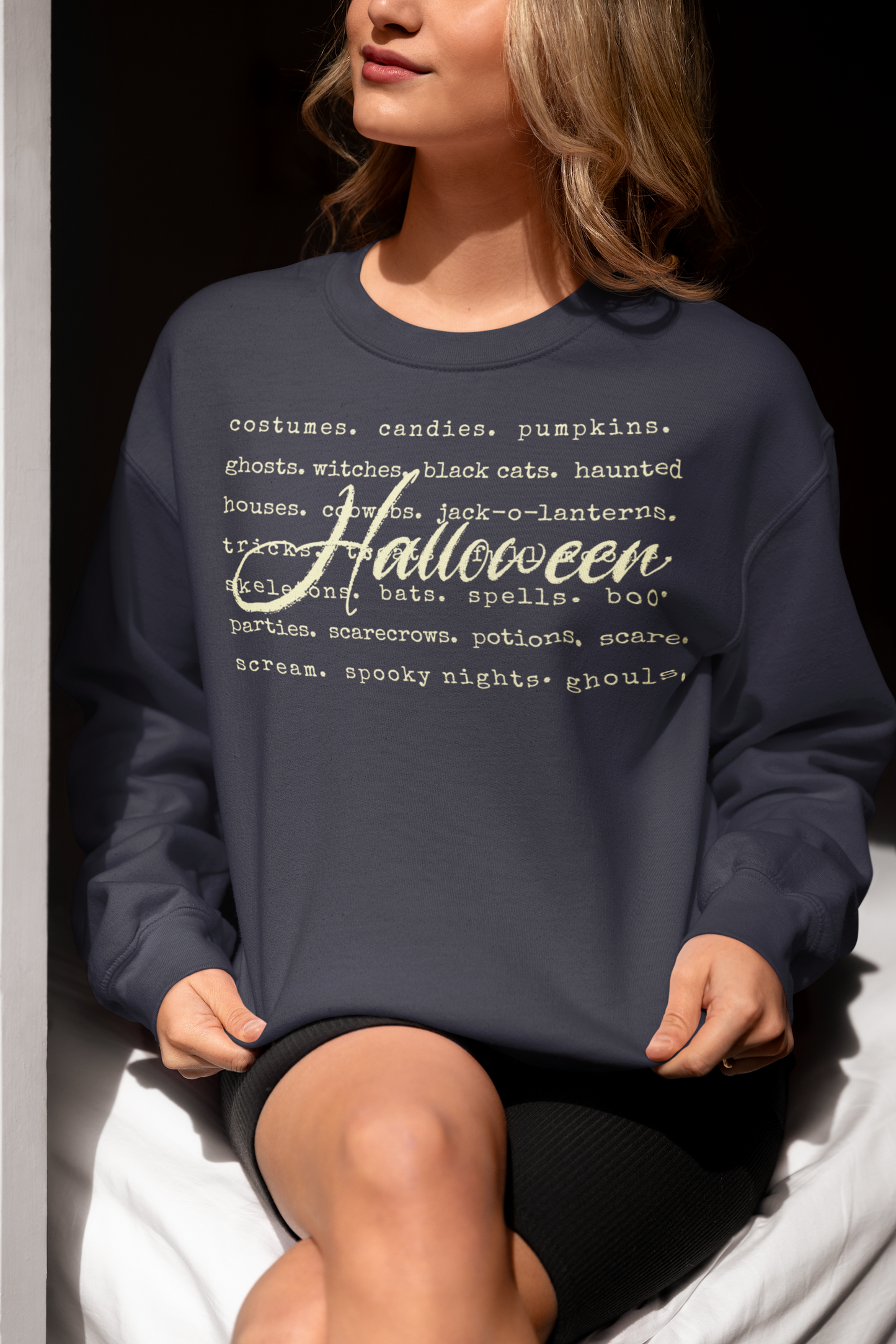 Person wearing a navy blue sweatshirt with Halloween-themed text.