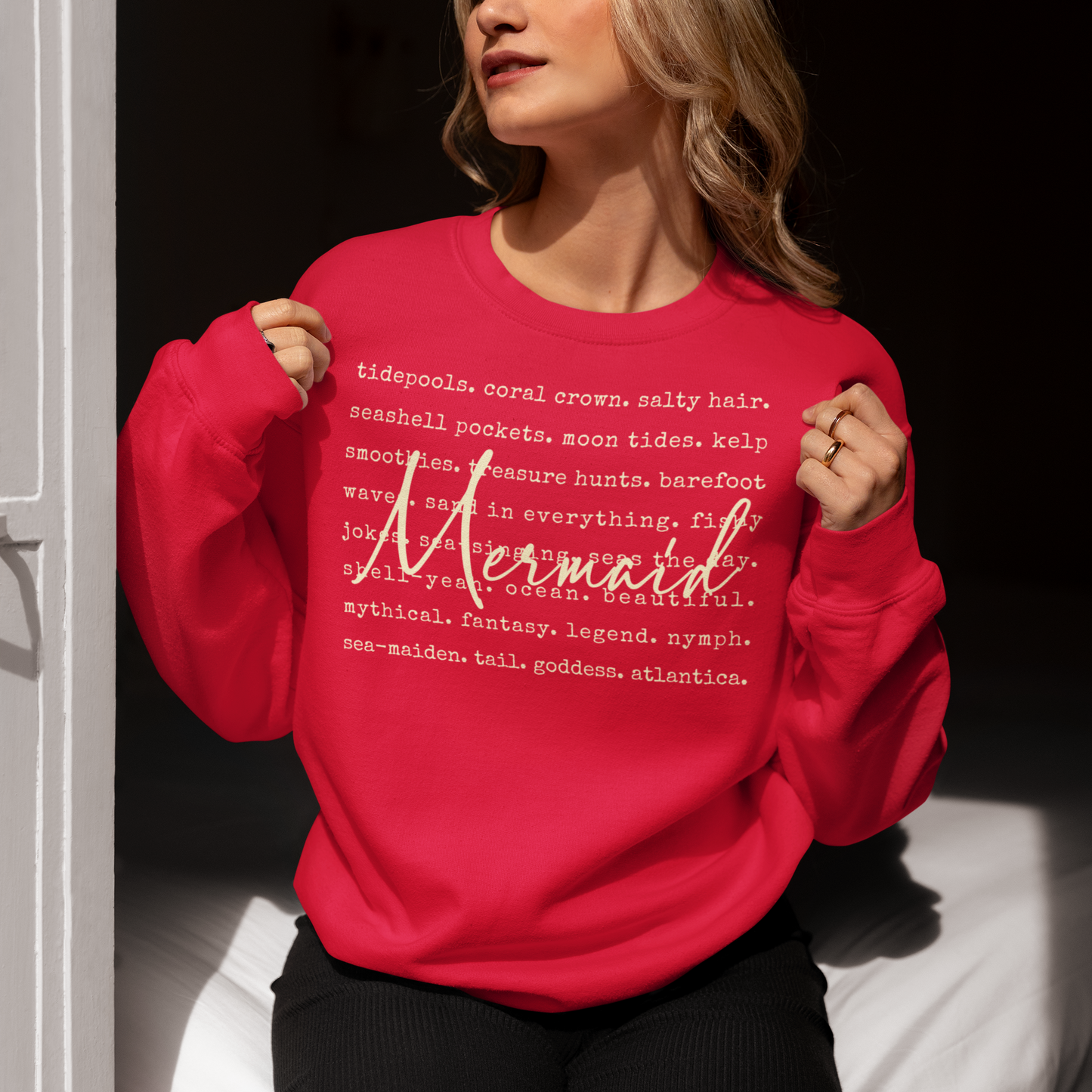 Person wearing a red sweatshirt with 'Mermaid' text design.