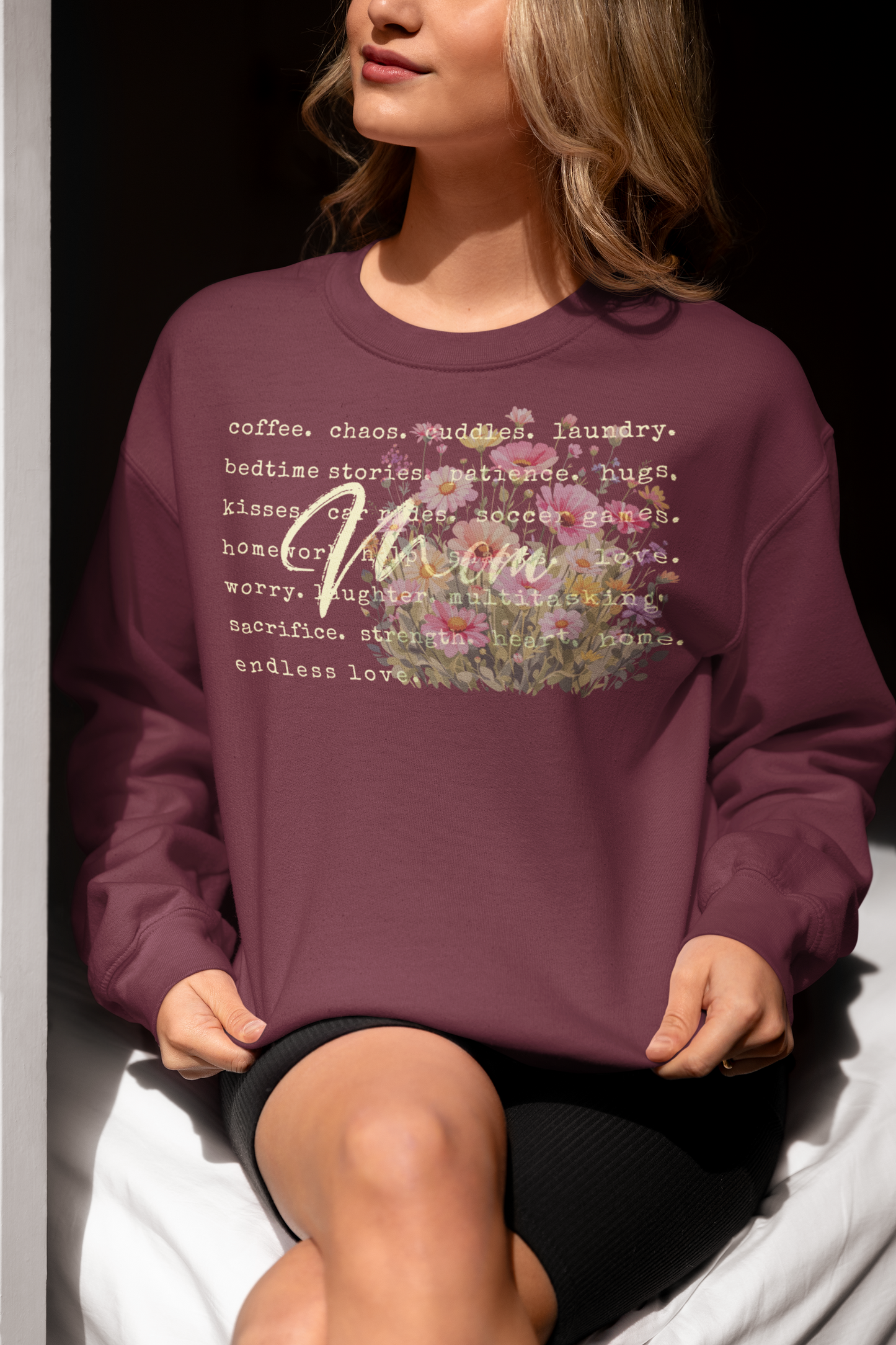 Person wearing a maroon sweatshirt with text and floral design