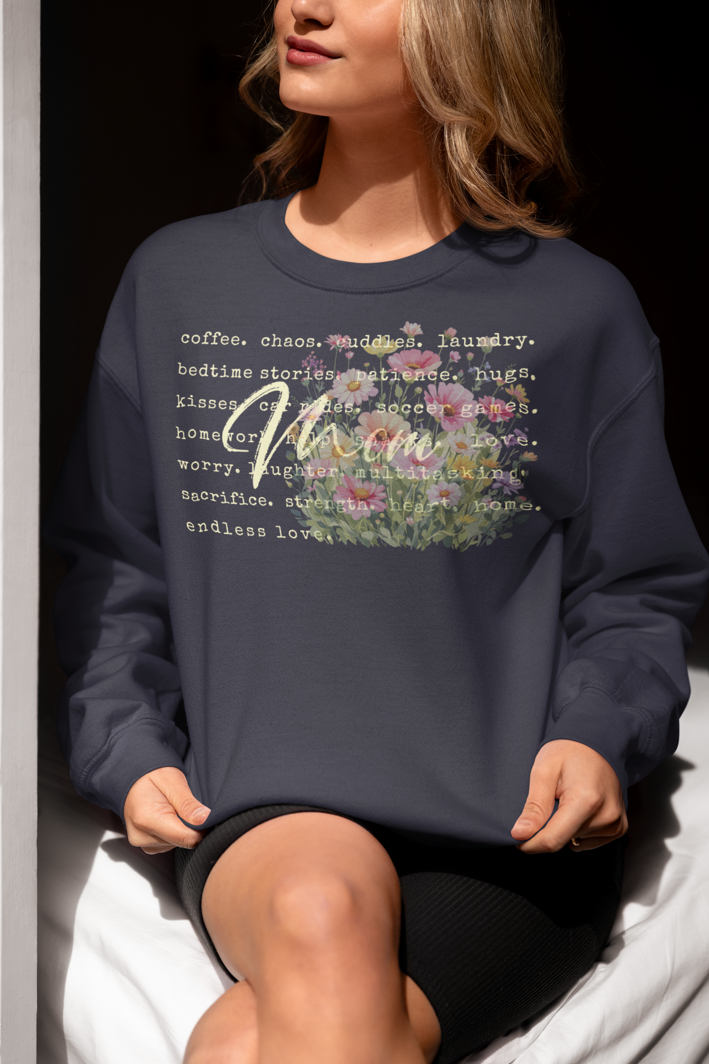 Person wearing a navy sweatshirt with floral text design