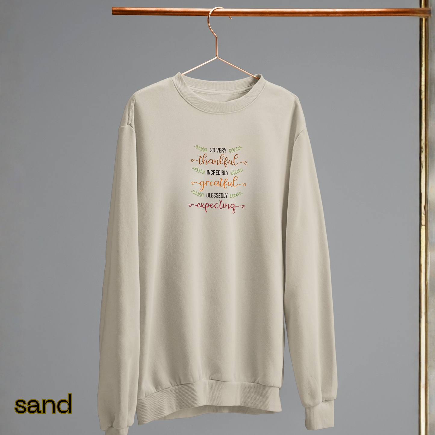 Beige sweatshirt with text on a hanger against a gray background