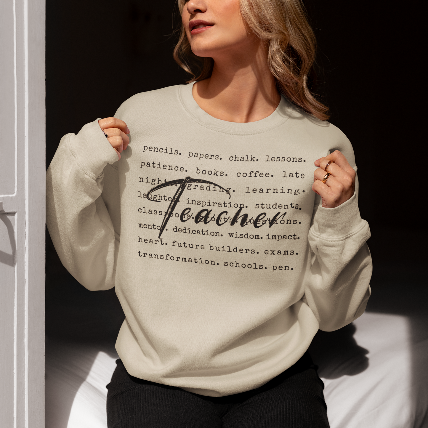 Person wearing a beige sweatshirt with text design, sitting on a white couch.