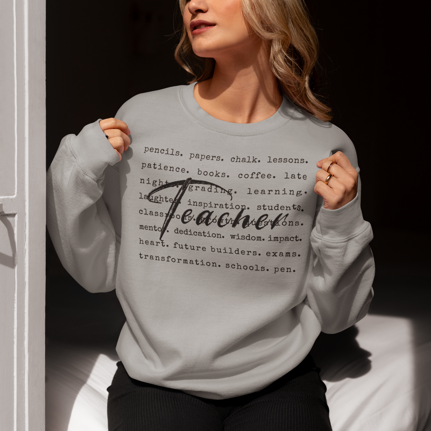 Person wearing a gray sweatshirt with text on it, sitting against a dark background.