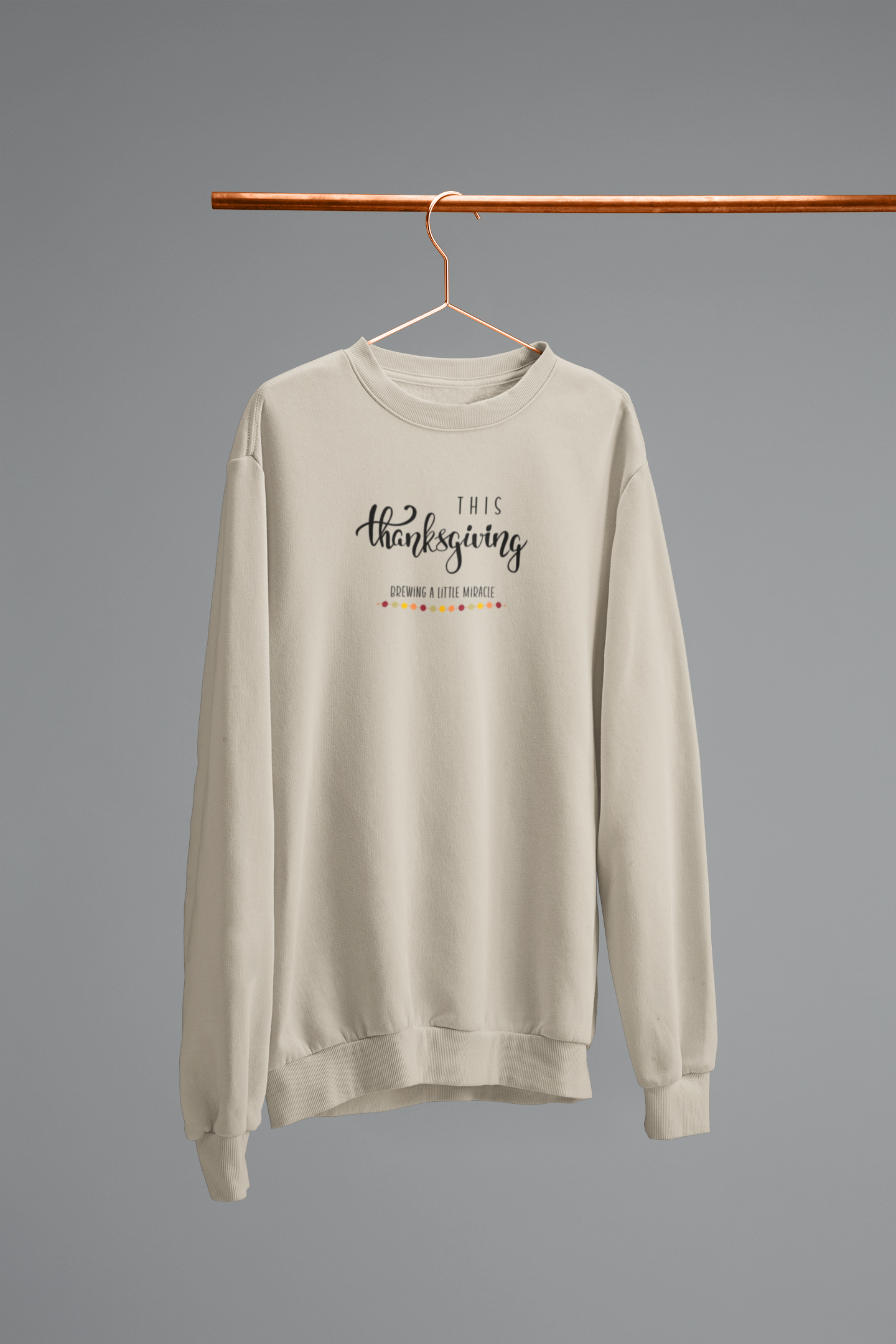 Beige sweatshirt with text on a hanger against a gray background