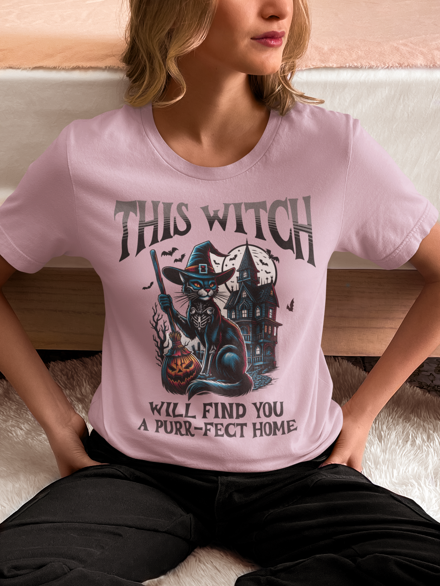 Person wearing a pink t-shirt with a Halloween-themed graphic and text.