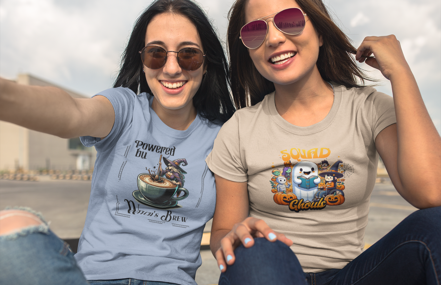 Two women sitting outdoors wearing t-shirts with Halloween-themed designs.