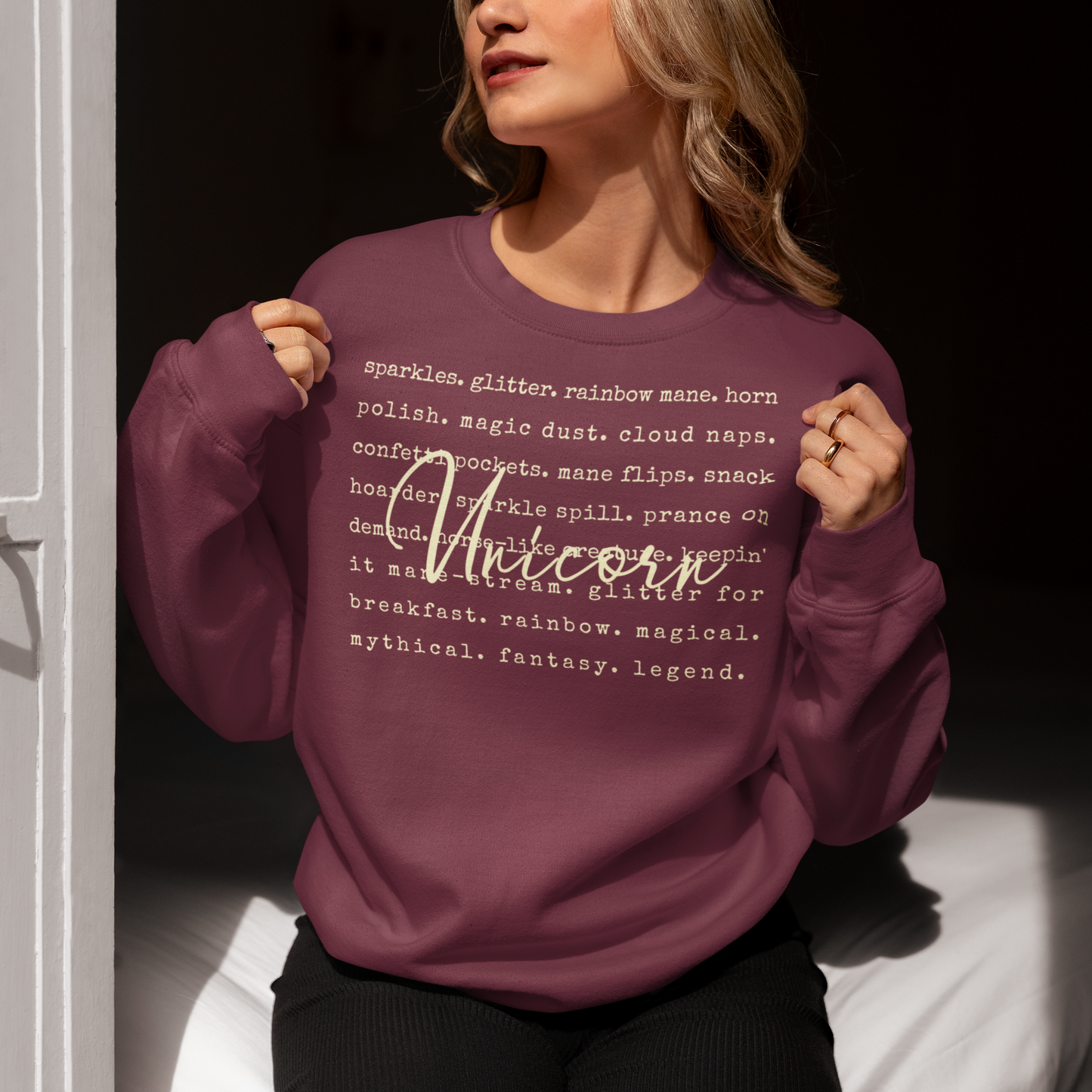 Person wearing a purple sweatshirt with text and the word 'Unicorn' on it.