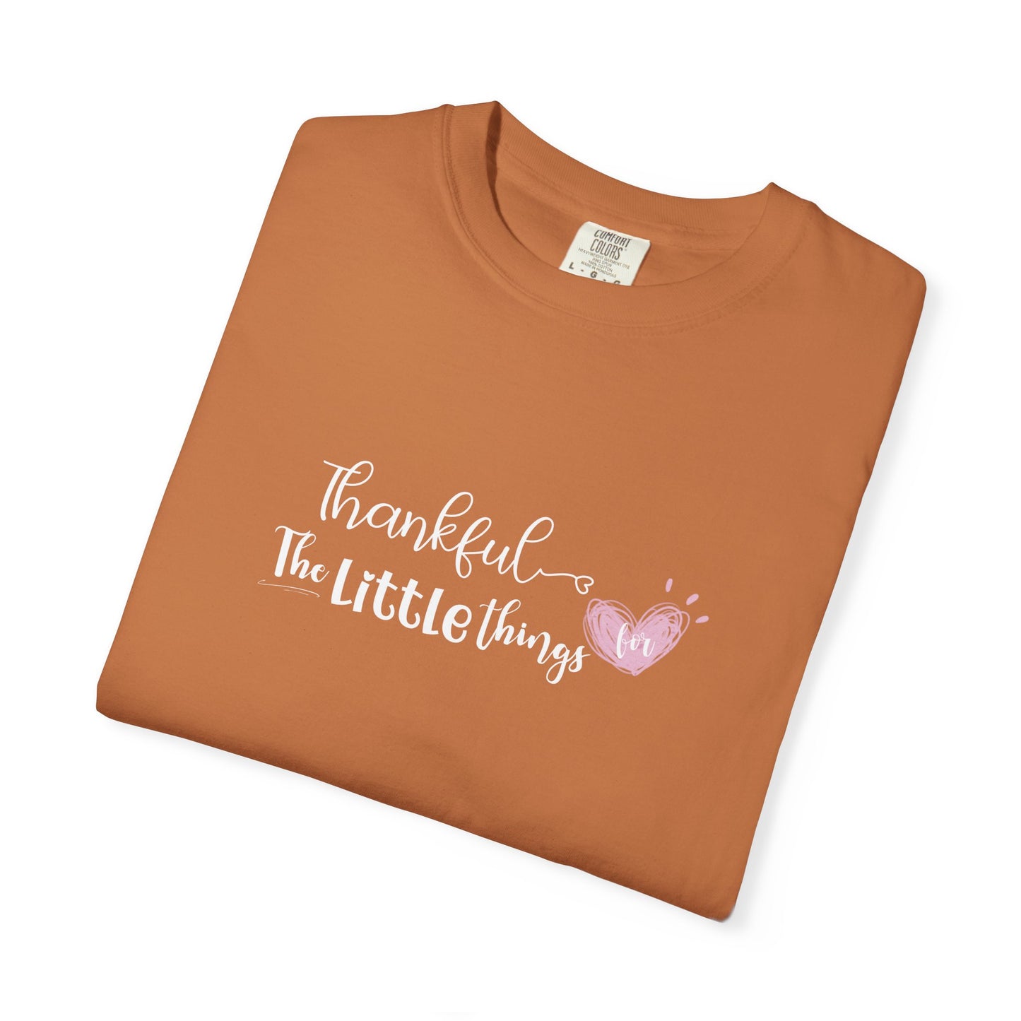 Folded brown t-shirt with 'Thankful for the little things' text and heart design on a white background