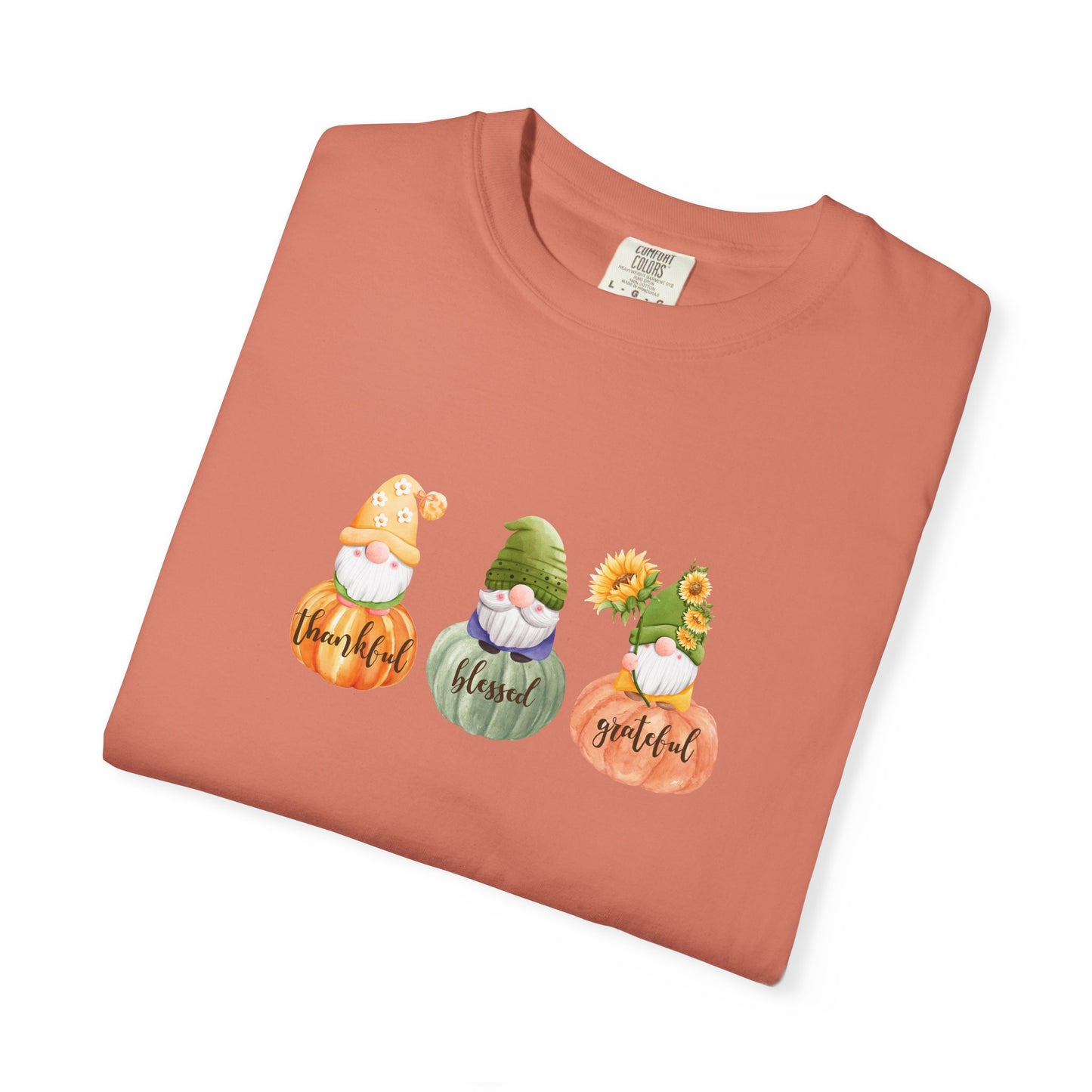 Folded terracotta-colored t-shirt with gnomes and text on a white background