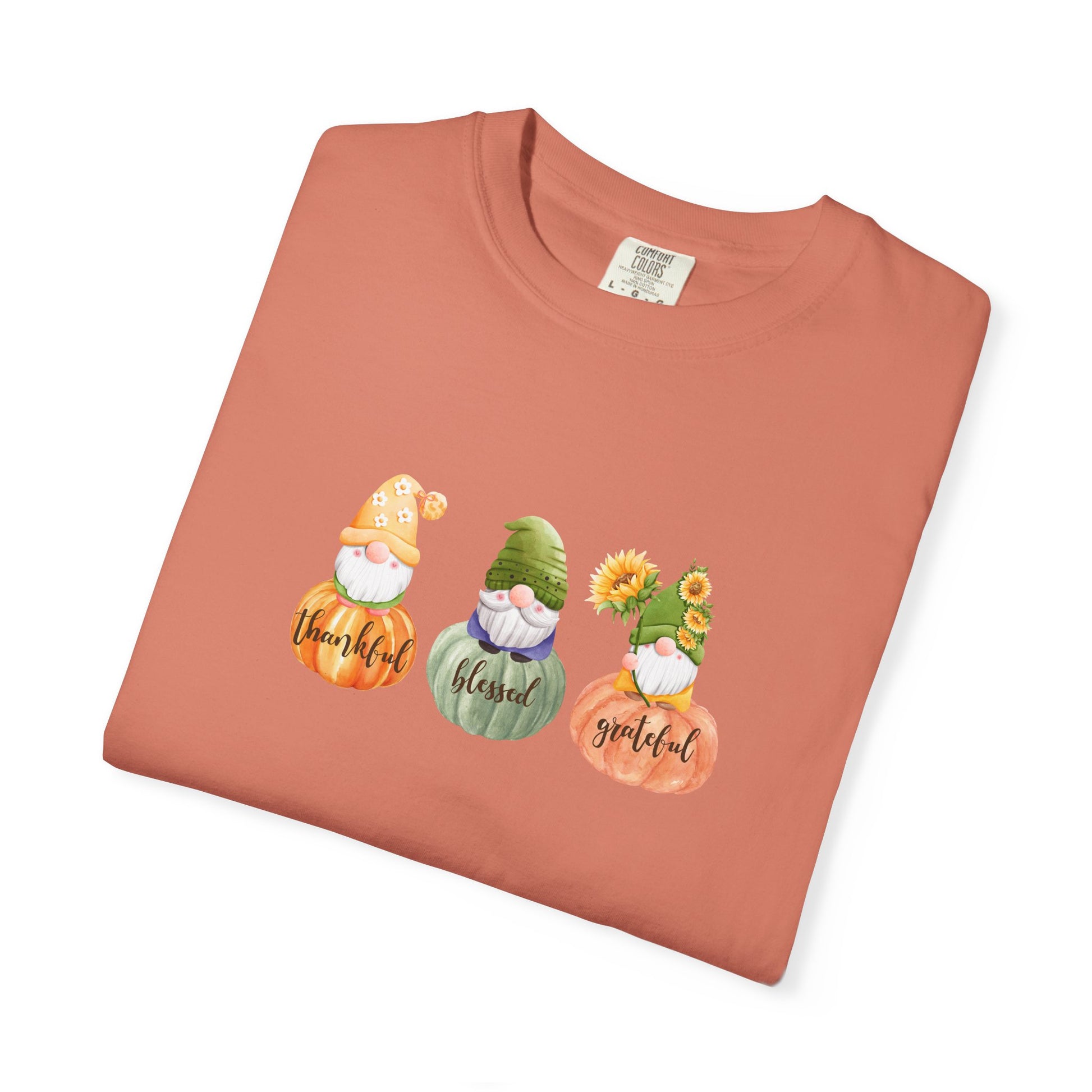 Folded terracotta-colored t-shirt with gnomes and text on a white background
