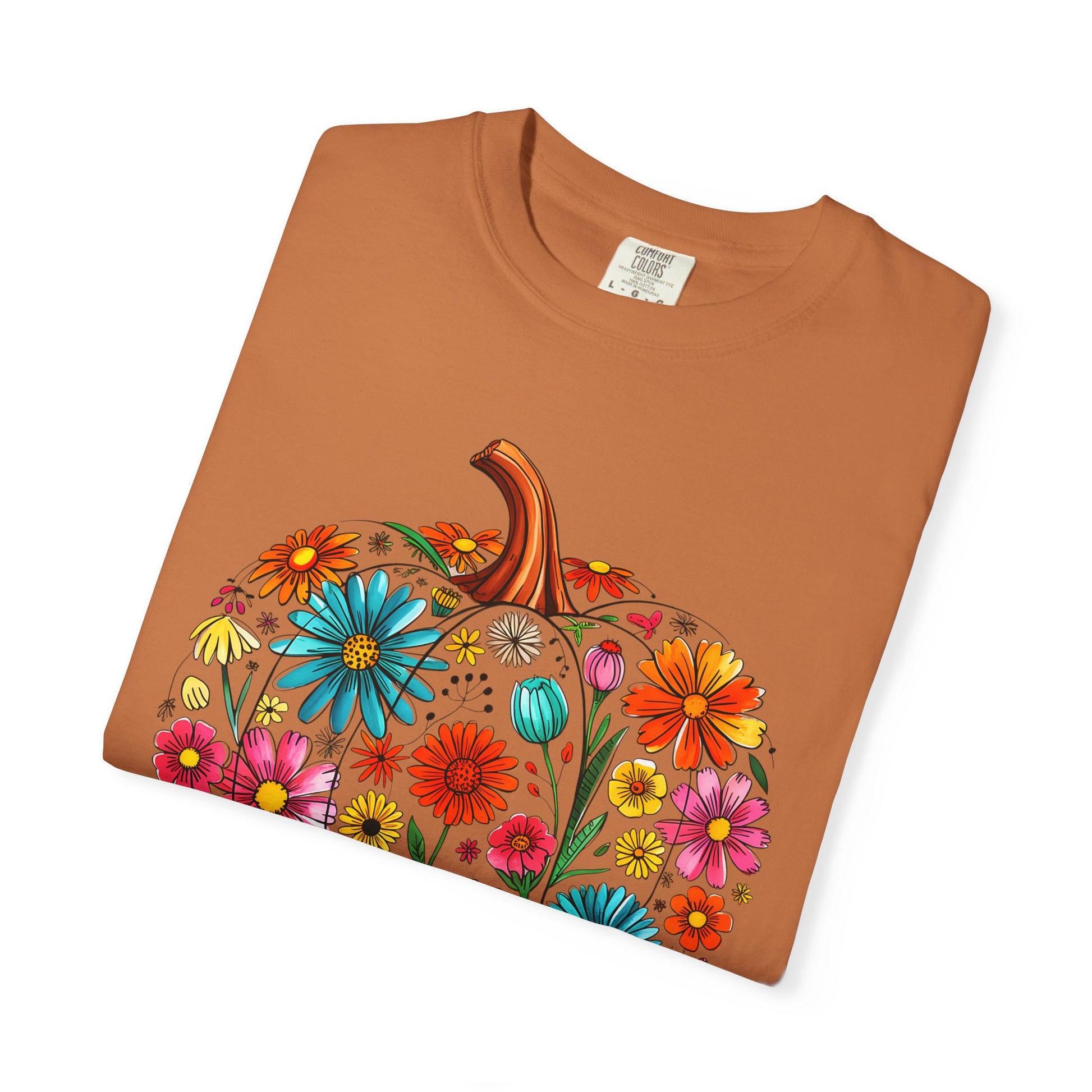 Folded brown t-shirt with a colorful pumpkin and floral design on a white background