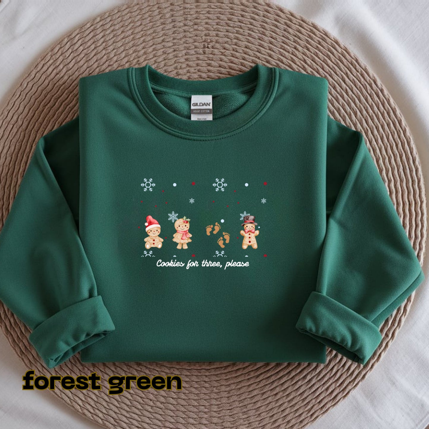 Green sweatshirt with Christmas-themed design on a woven mat