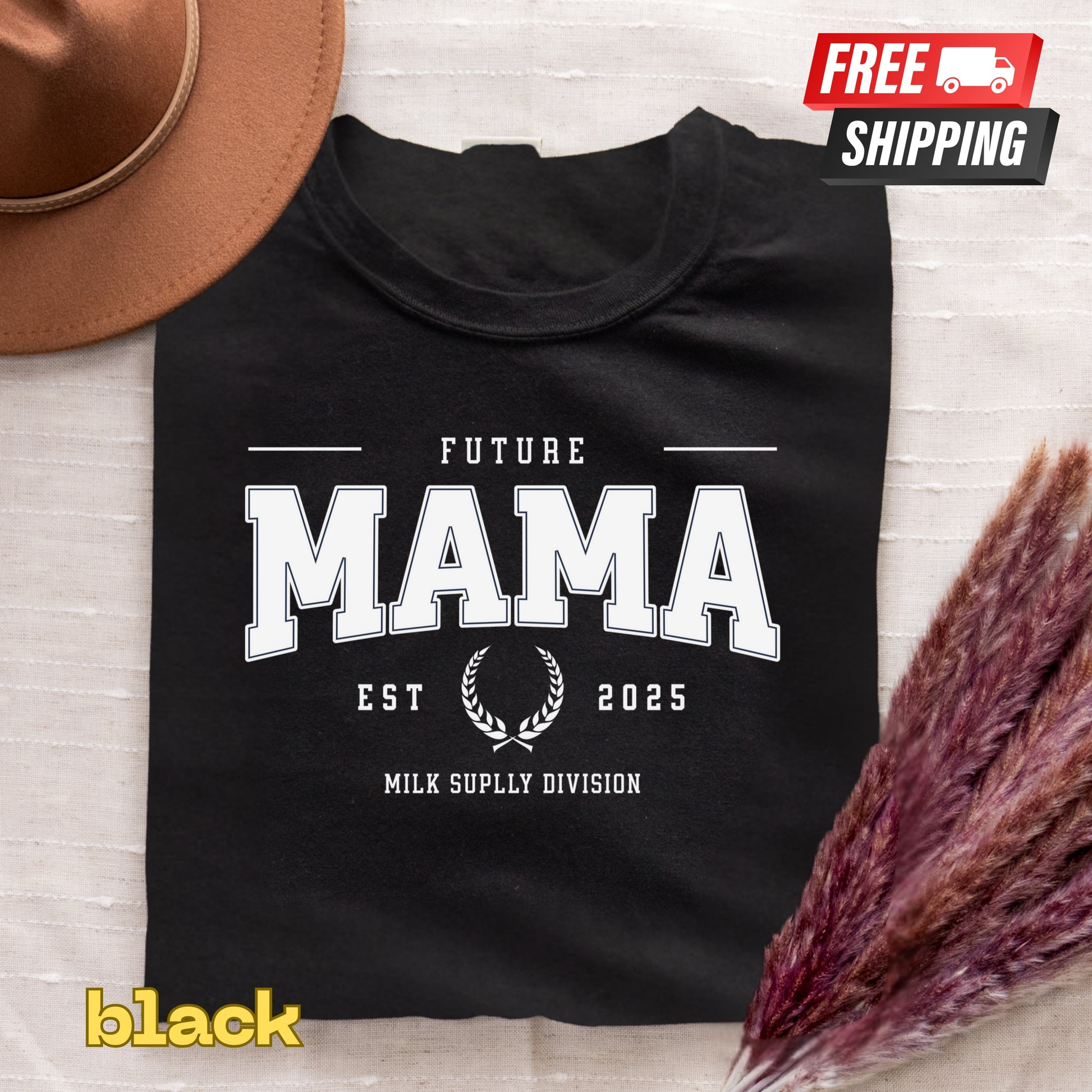 Black t-shirt with 'Future Mama' text on a textured surface with a hat and dried flowers.
