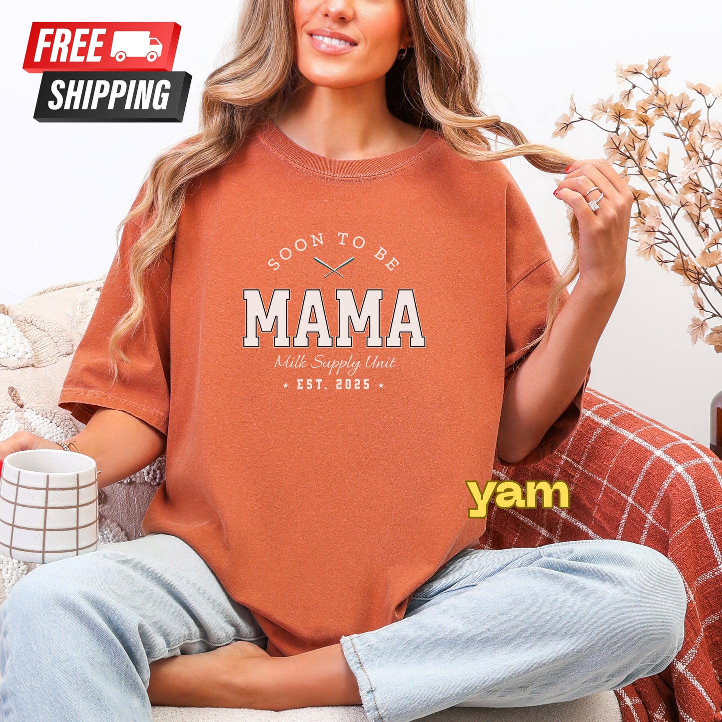 Woman wearing a 'Soon to be Mama' t-shirt with 'yam' branding, sitting on a couch.