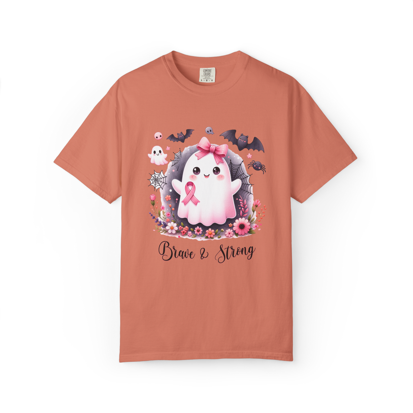 Coral t-shirt with a cartoon ghost wearing a pink bow and ribbon, surrounded by flowers and text 'Brave & Strong' on a white background.