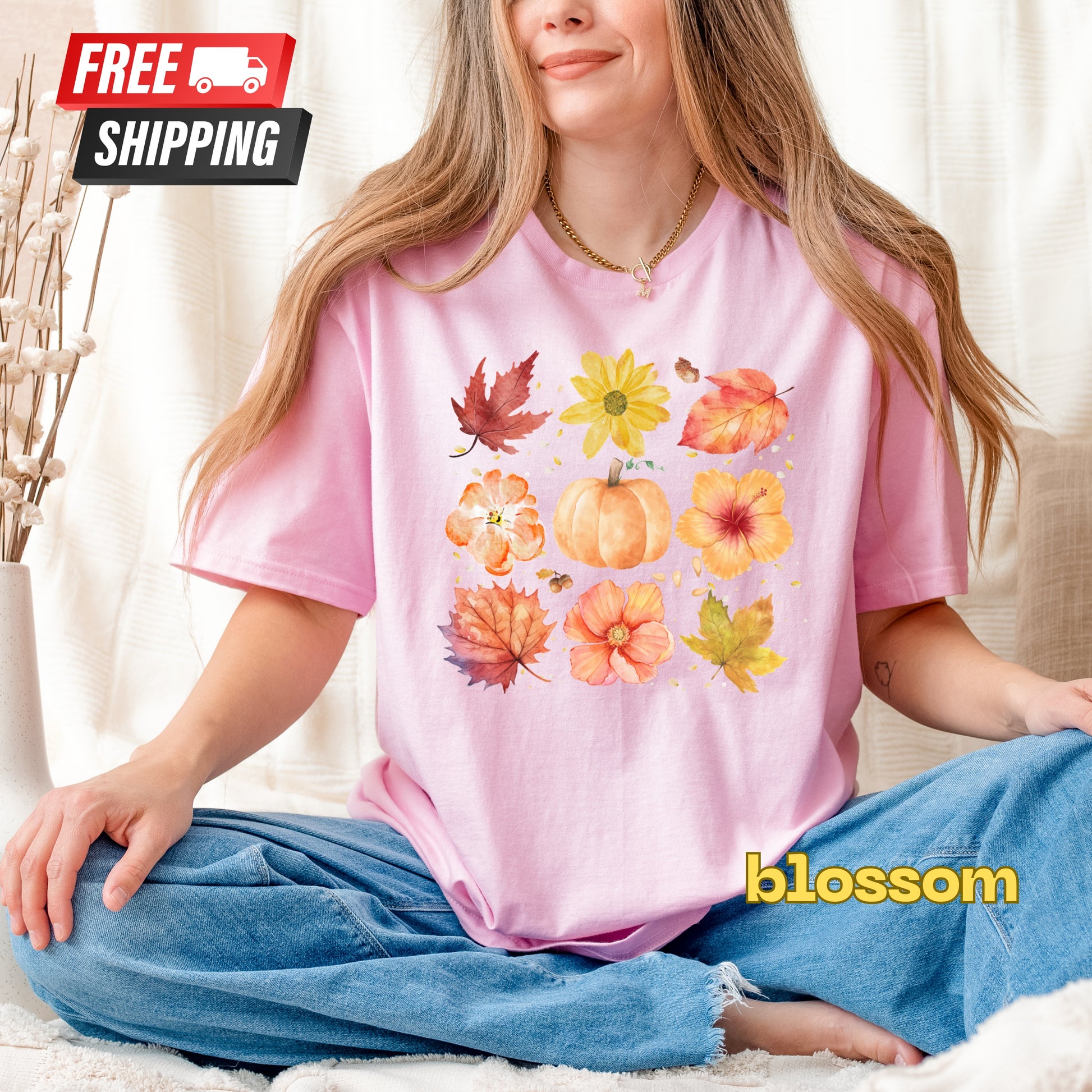 Person wearing a pink t-shirt with autumn-themed design, sitting on a couch.