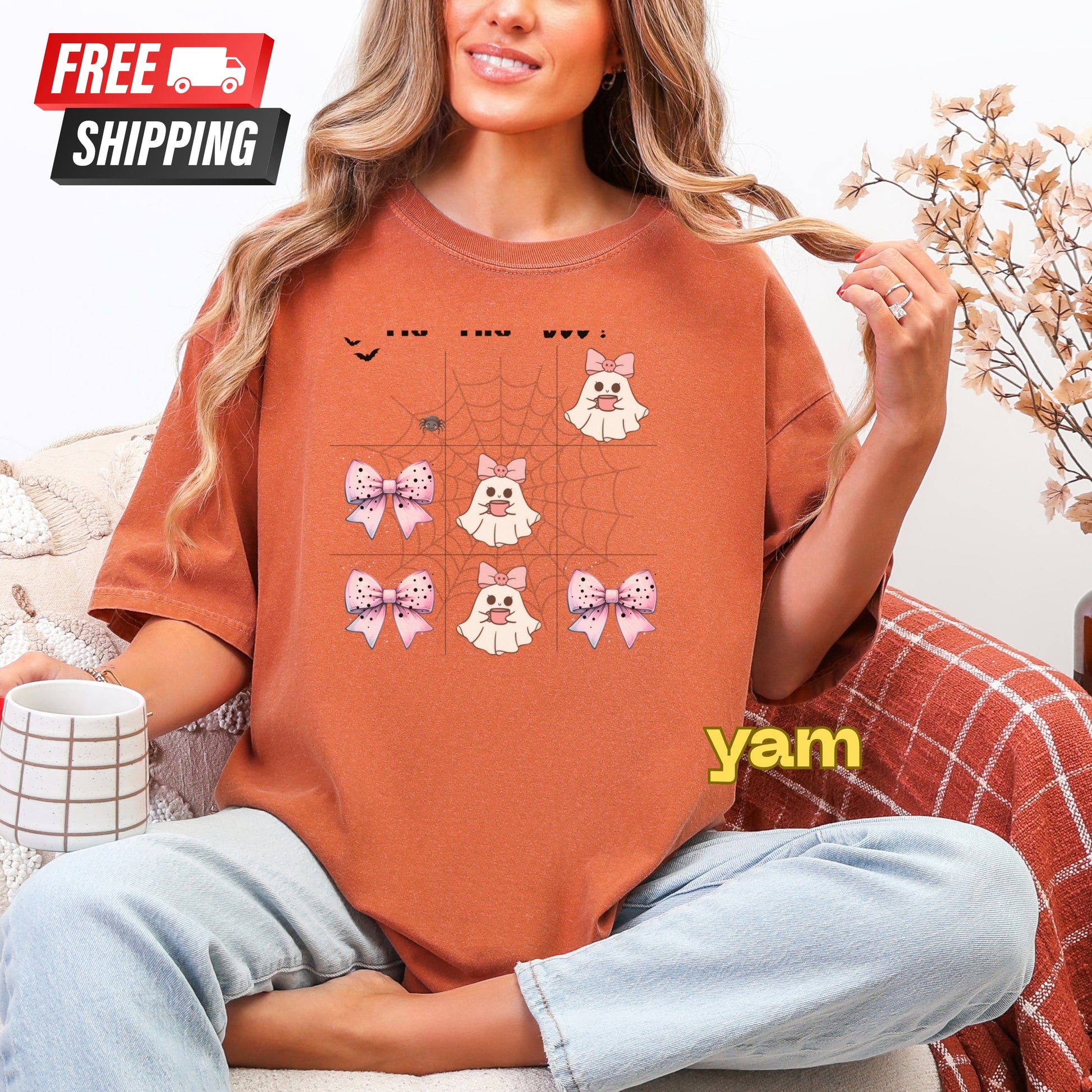 Person wearing an orange t-shirt with graphics and 'yam' text, sitting on a couch with free shipping label.