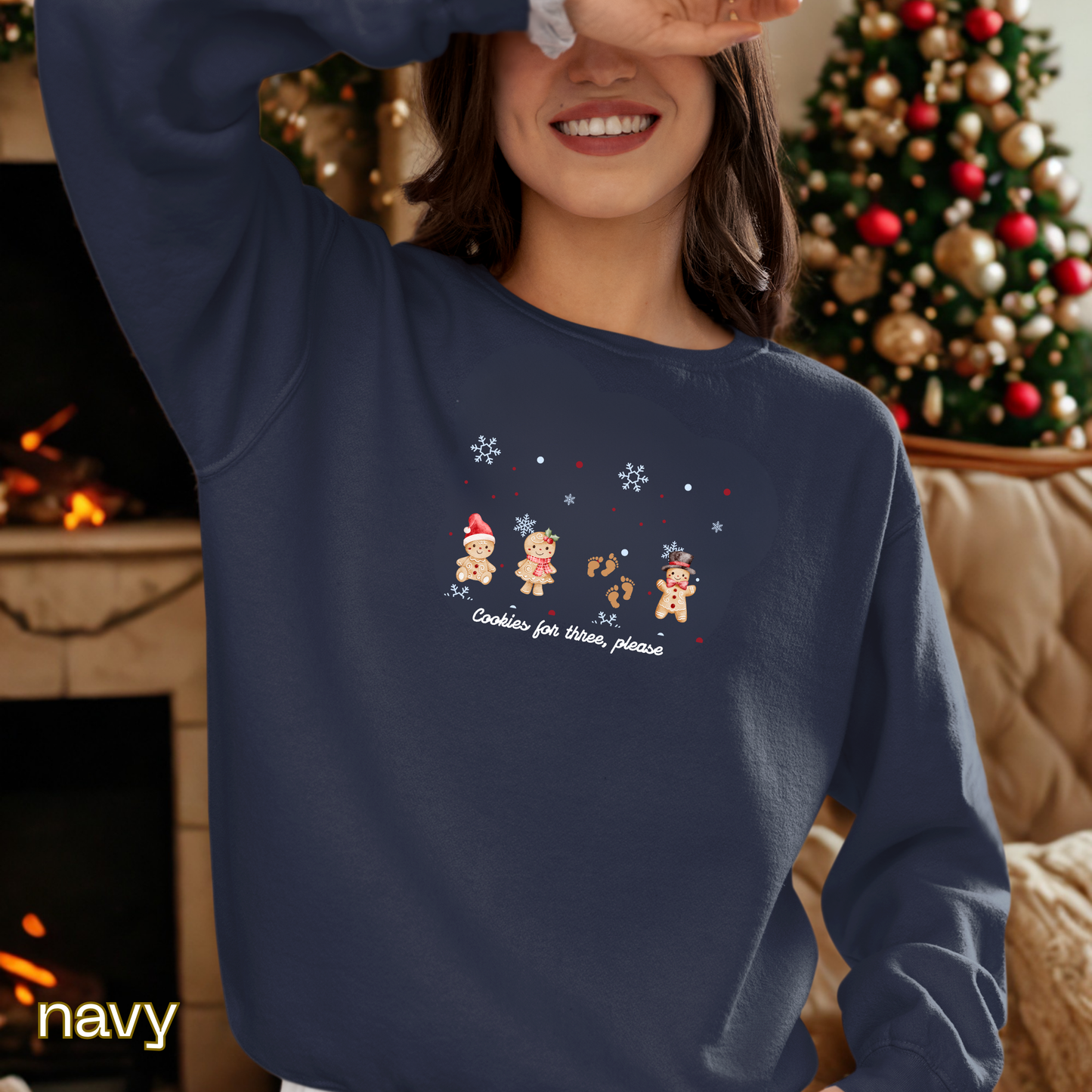 Person wearing a navy sweatshirt with Christmas-themed design in front of a decorated Christmas tree.