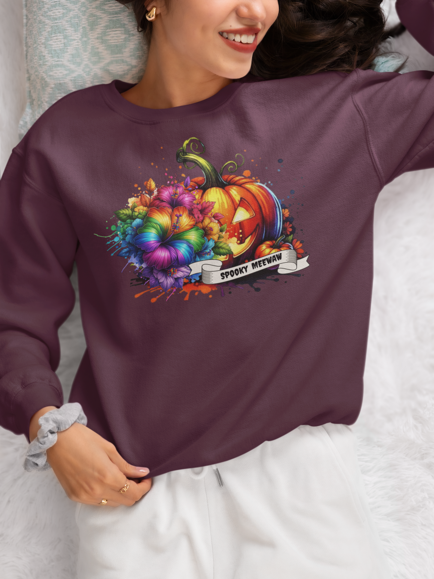 Person wearing a maroon sweatshirt with a colorful pumpkin design and text.